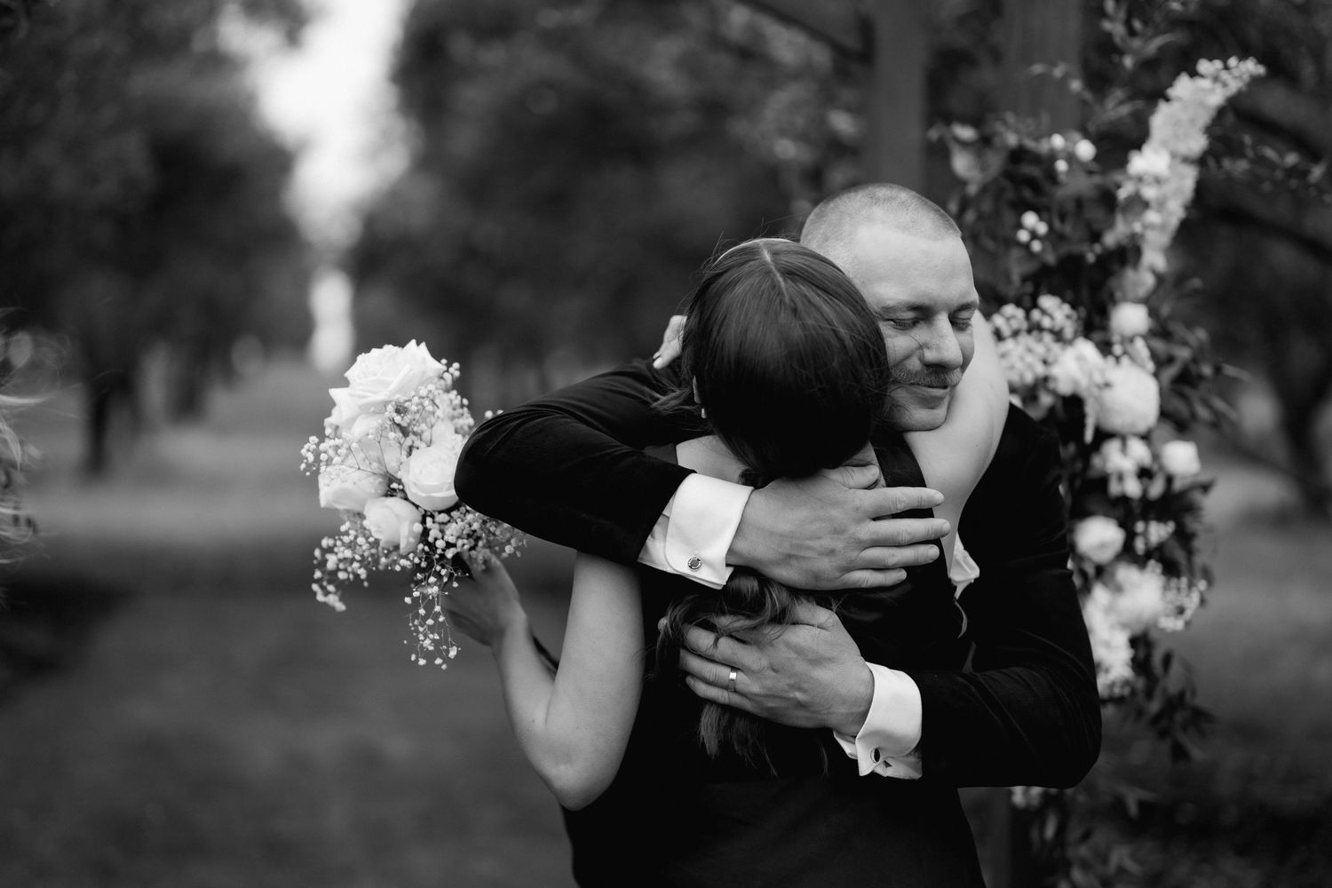 An emotional black and white photograph capturing a tender embrace during a wedding ceremony.