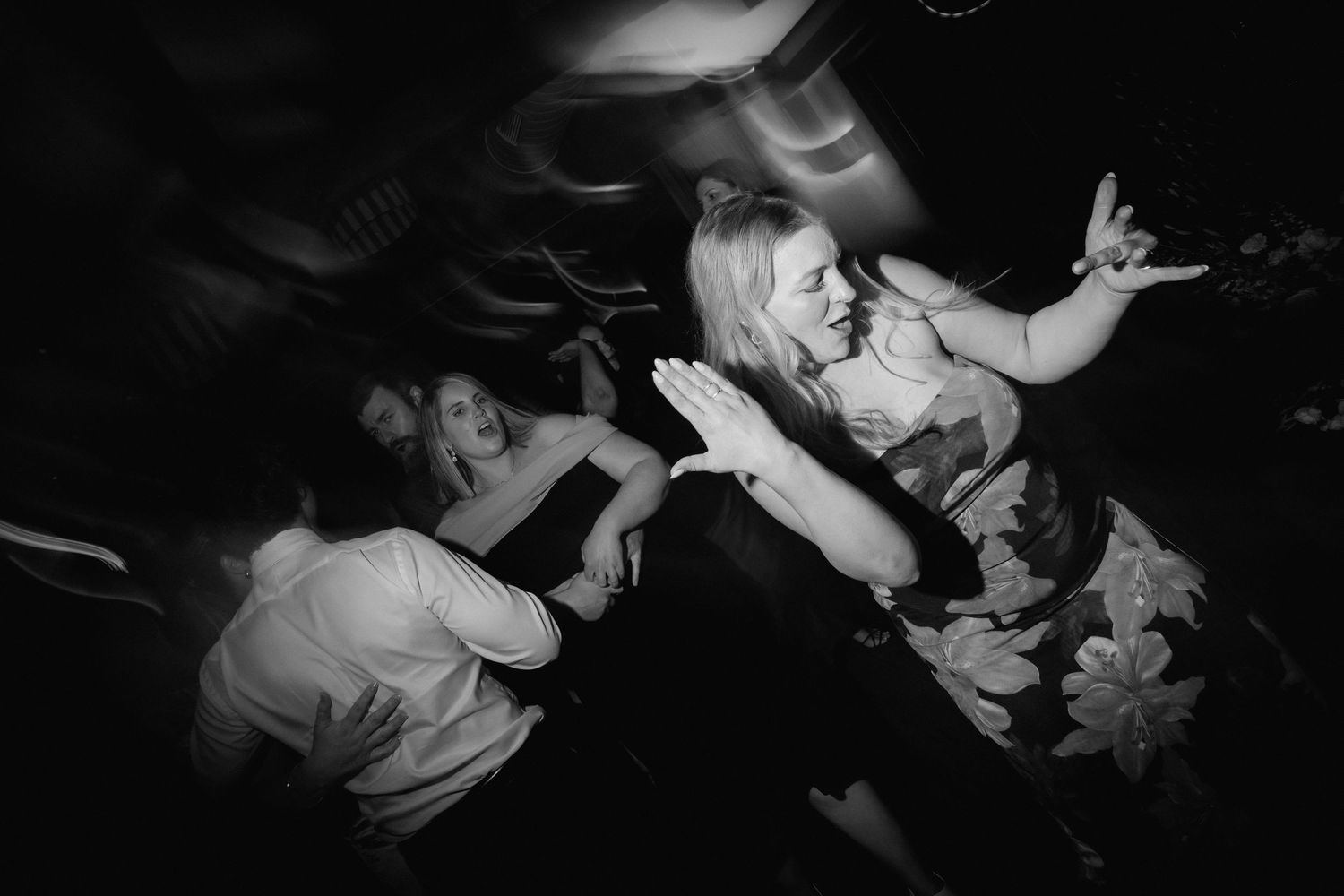 Wedding reception dance floor captured in dramatic black and white lighting.