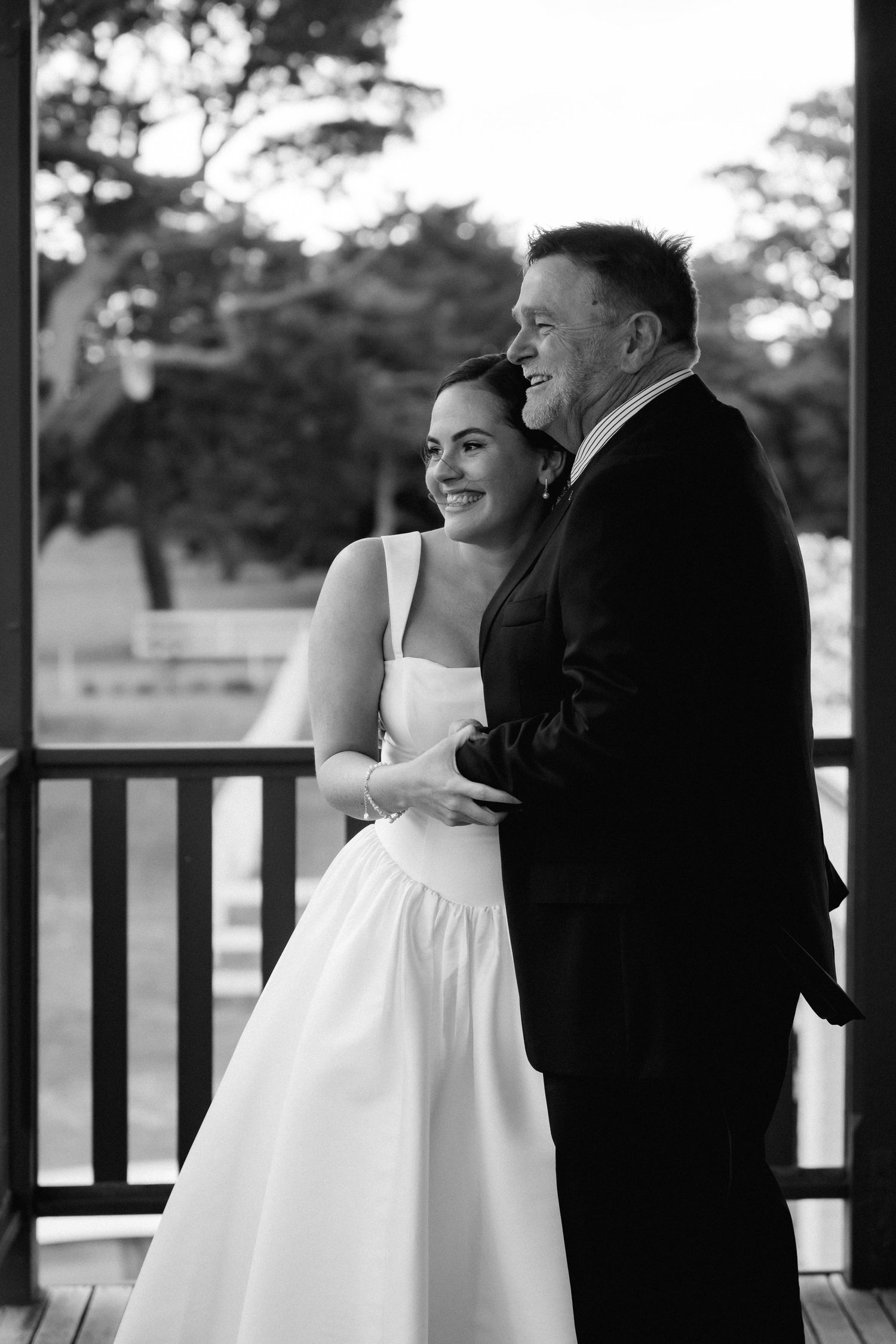 Black and white portrait of a couple sharing an intimate moment on a porch during their wedding day.