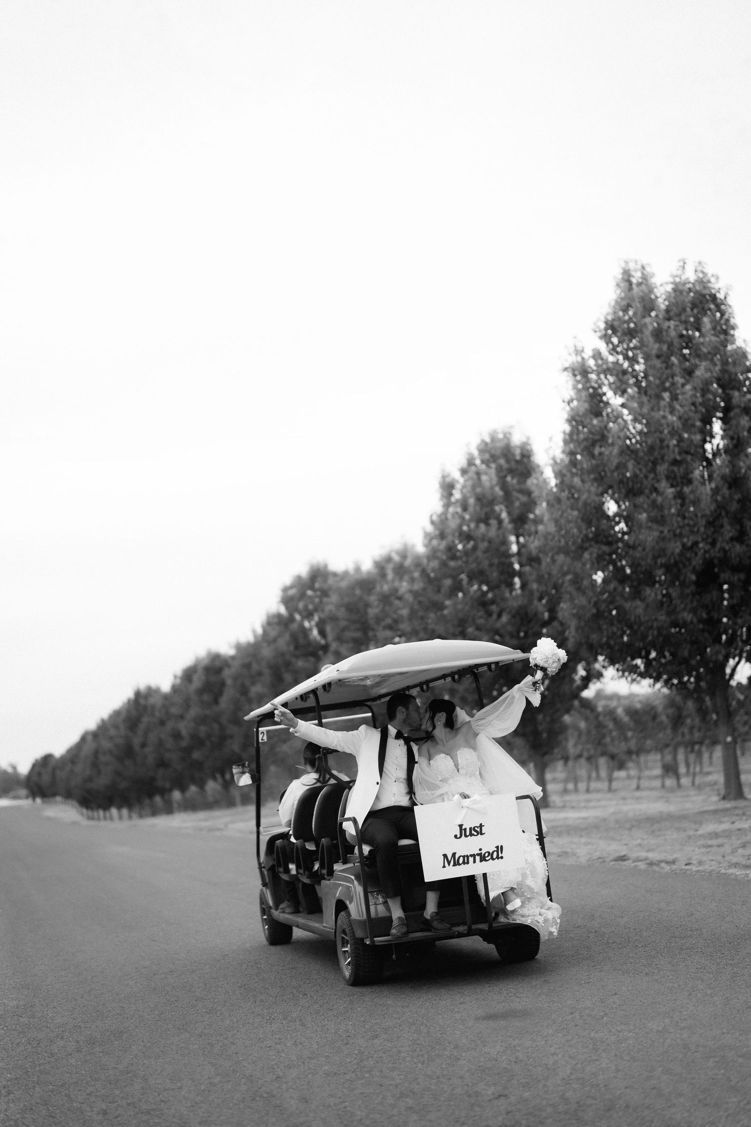 Black and white photo of a golf cart decorated with 'Just Married' sign.
