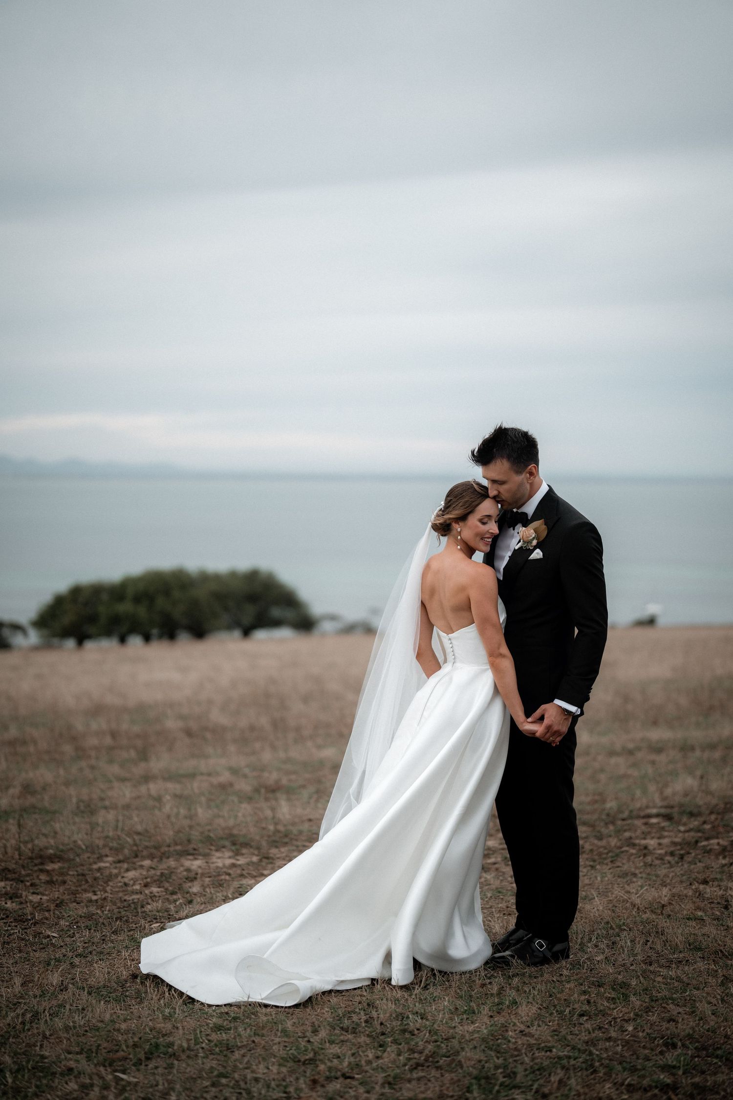 Newlyweds share an intimate moment together overlooking a coastal landscape.
