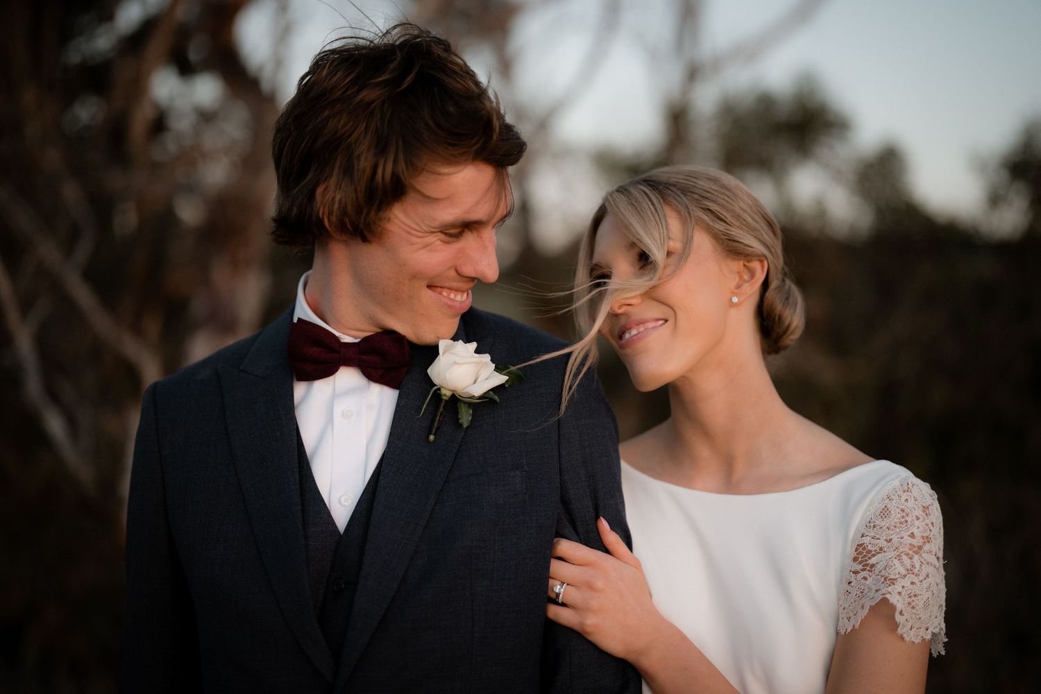 Romantic sunset portrait of couple in formal wedding attire.