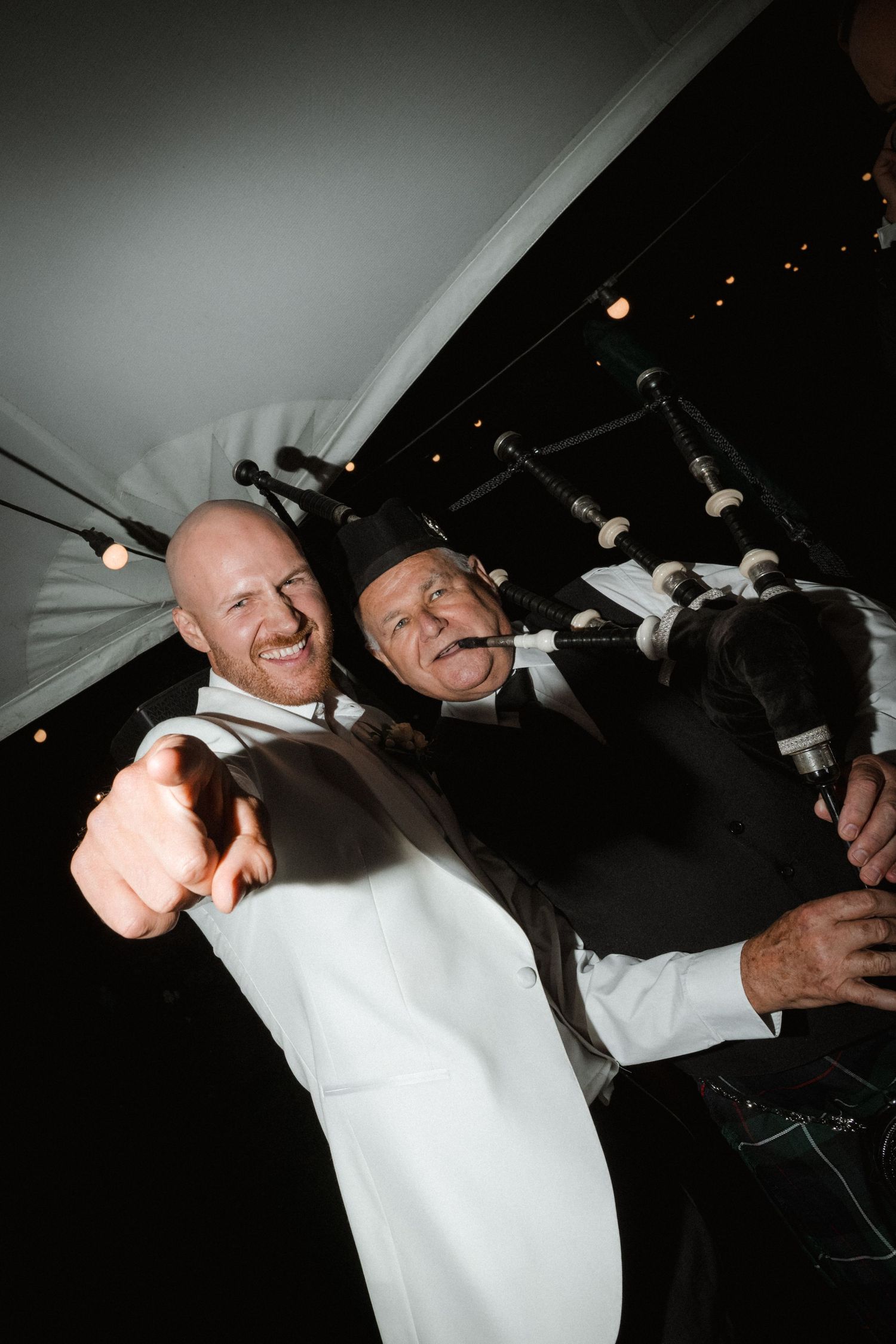 Joyful celebration moment under string lights at evening reception.