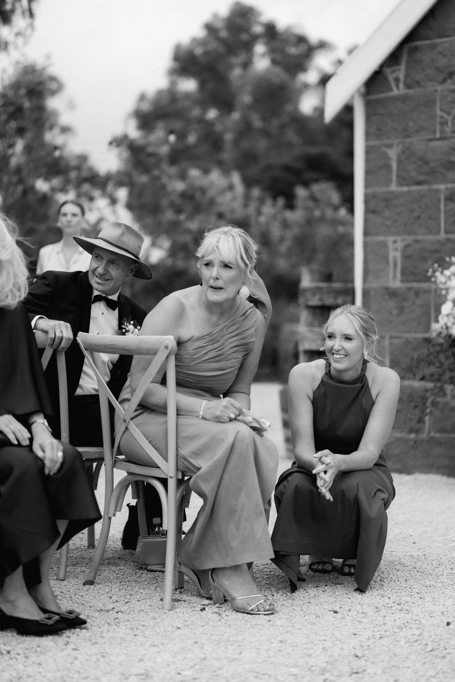 Wedding guests relaxing outdoors near a stone building.