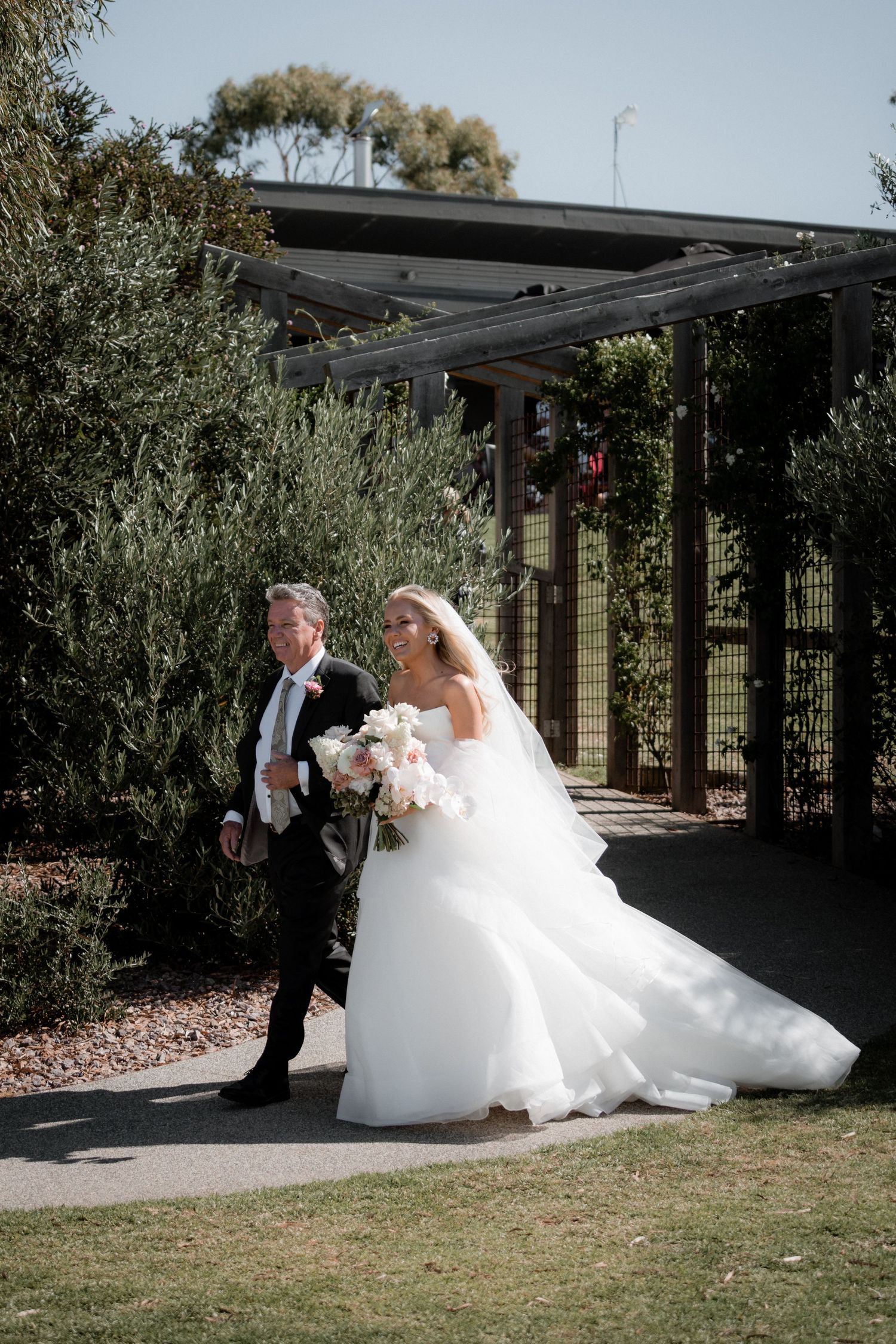 An elegant wedding ceremony setting with olive trees and modern architecture.