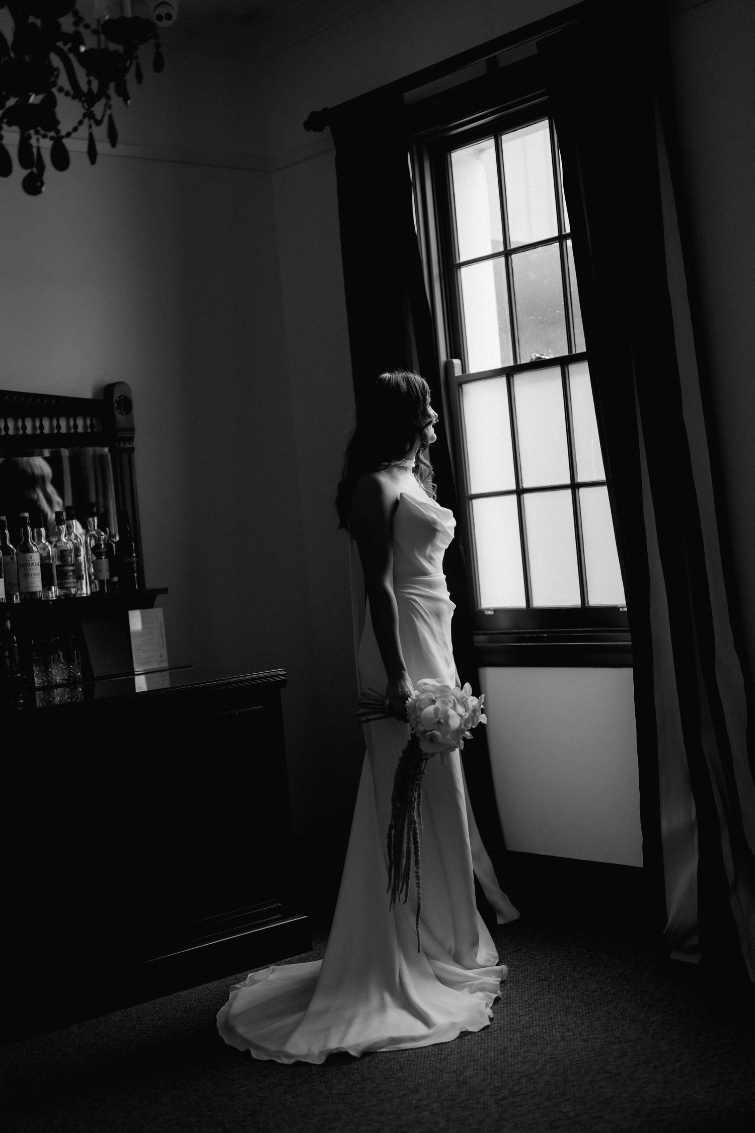 A series of dramatic black and white photos showing a wedding dress in an elegant indoor setting.