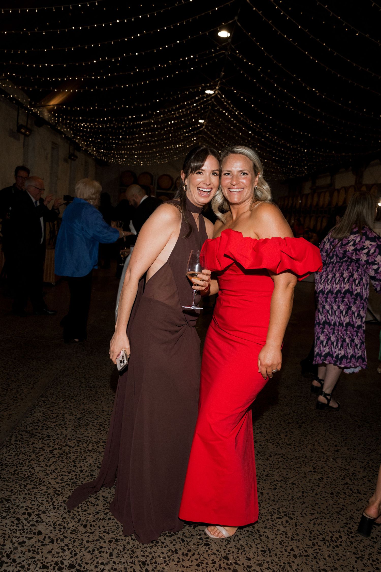 Wedding reception celebration with string lights overhead and guests in formal attire.