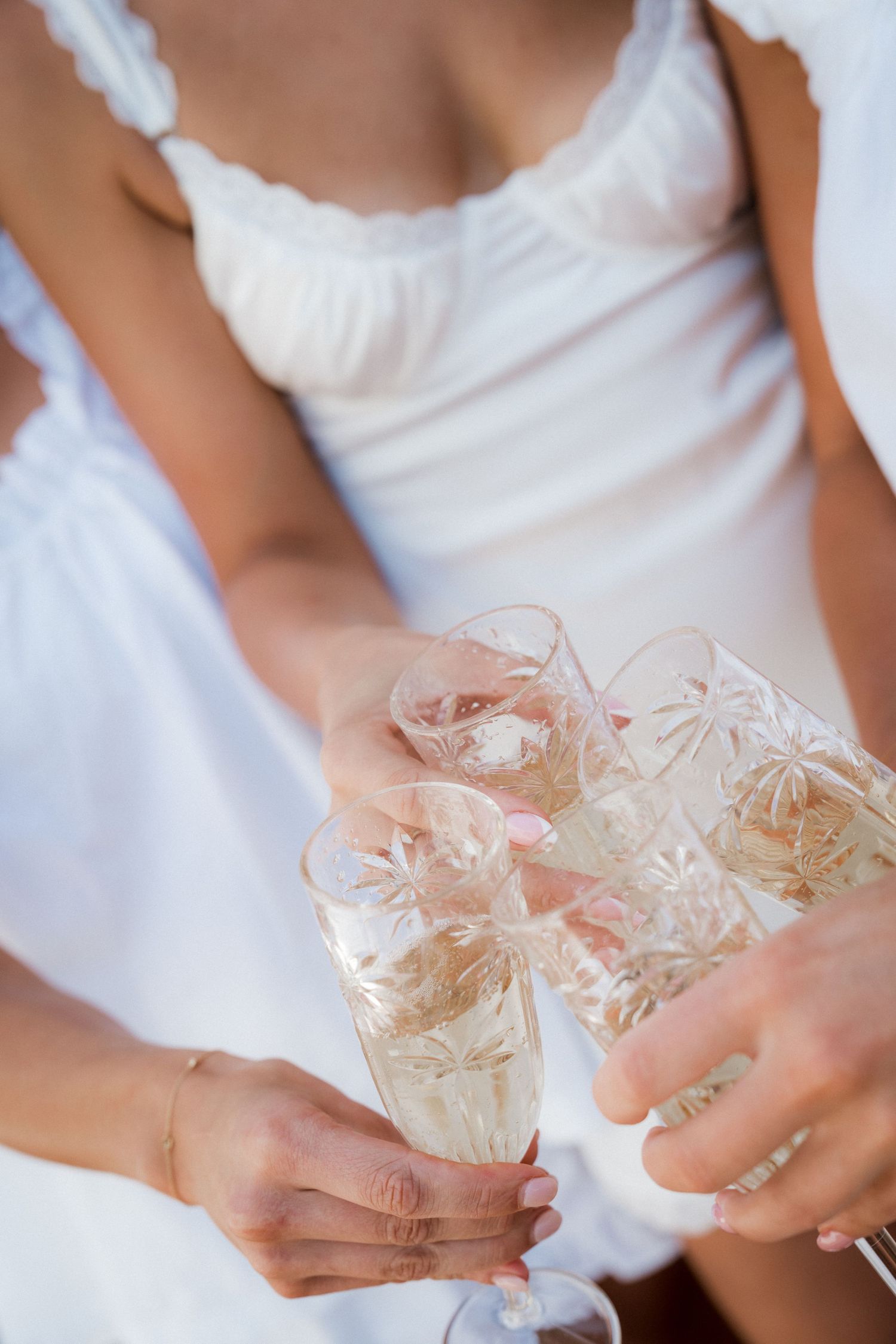 Delicate sheer fabric with floral lace details being held gently in hands against a white background.