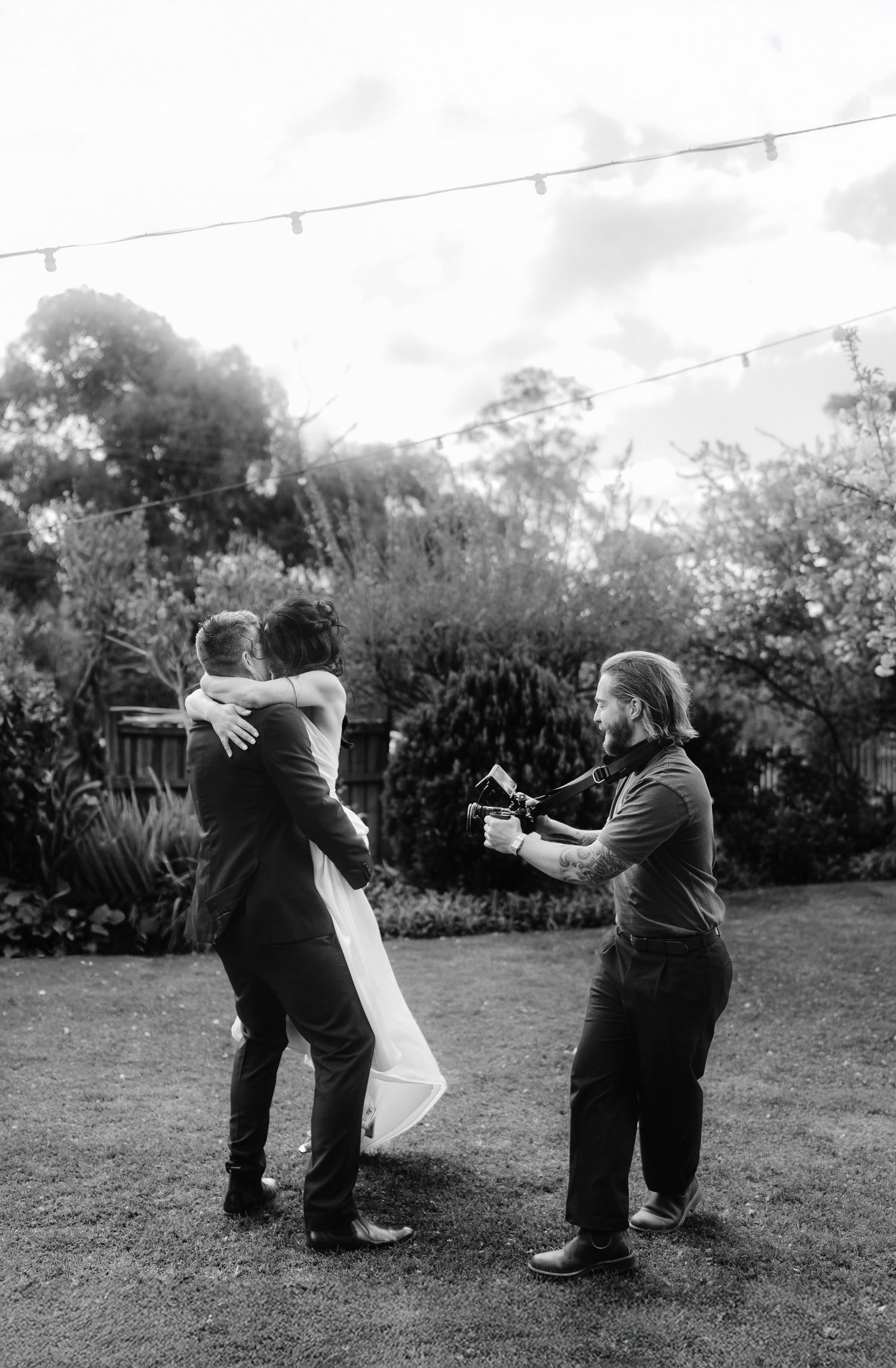 A sequence of black and white photos showing two people practicing martial arts moves outdoors in a garden setting.