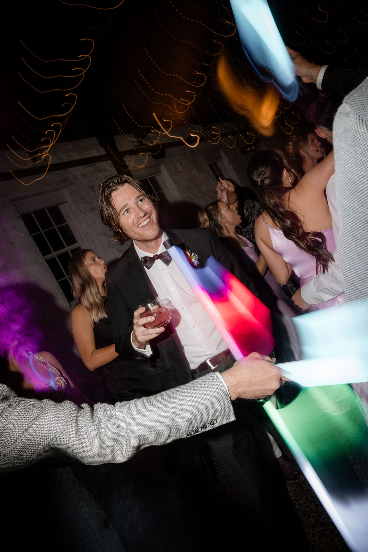 Dynamic dance floor photos capture wedding reception guests in motion under colorful party lights.