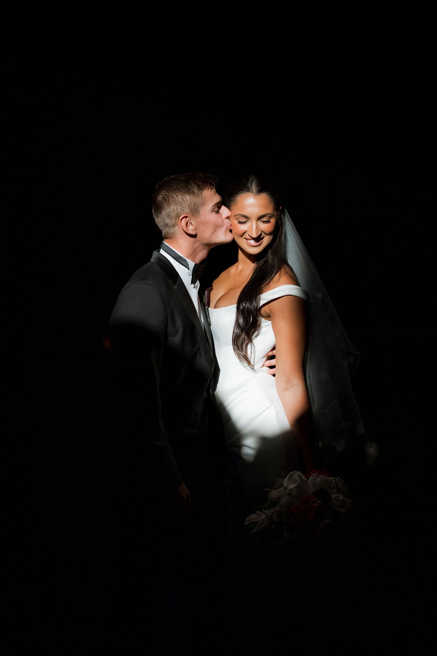 Dramatic black and white portrait of newlyweds in intimate lighting.