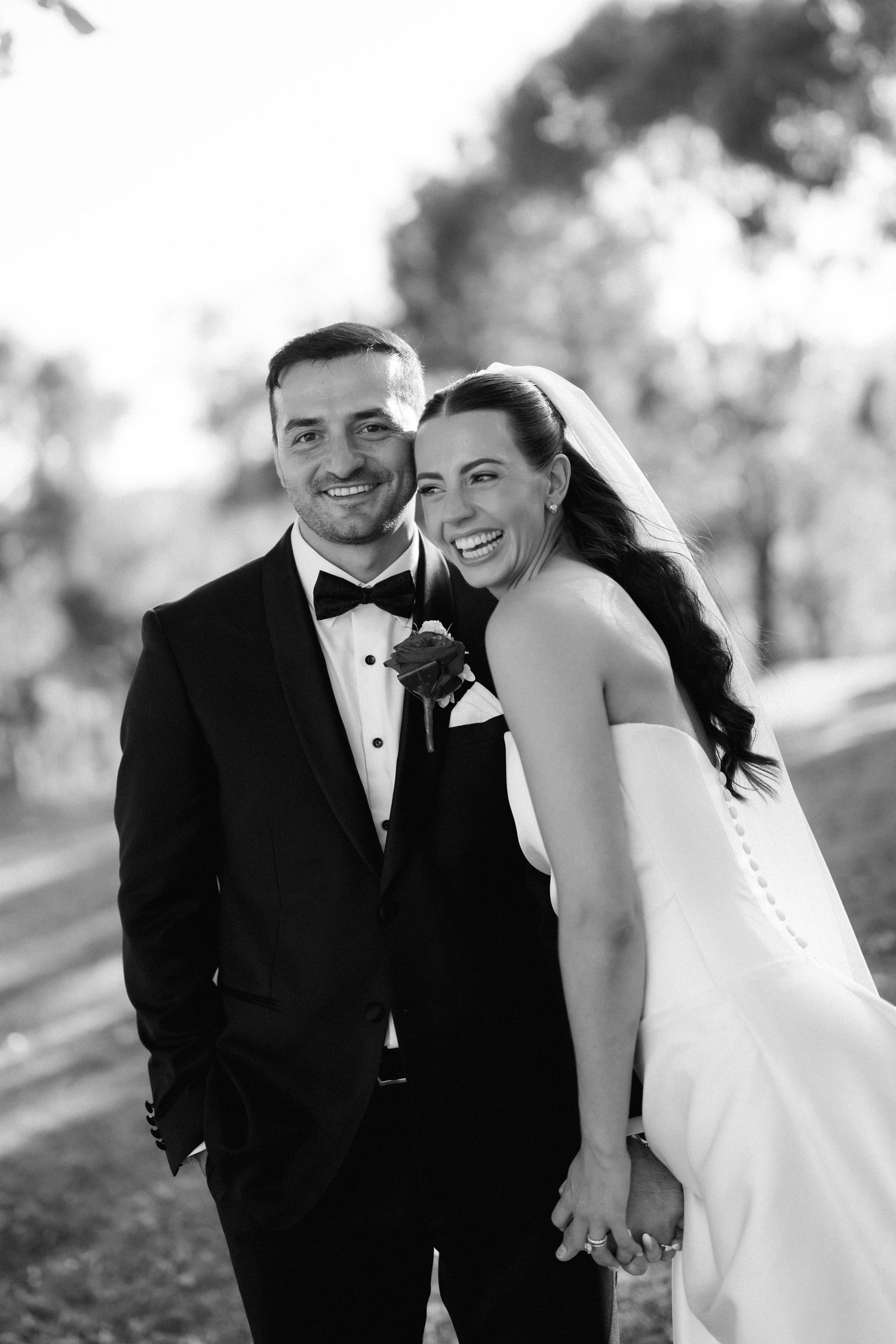 Black and white portrait of couple sharing intimate moment in formal wedding attire.