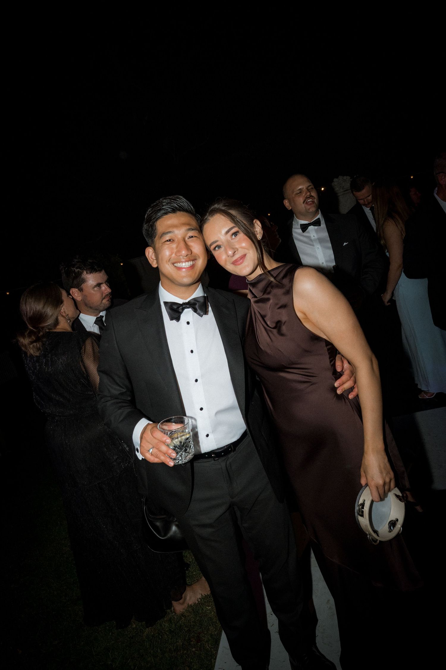 Wedding reception guests dance and celebrate at evening party in formal attire.