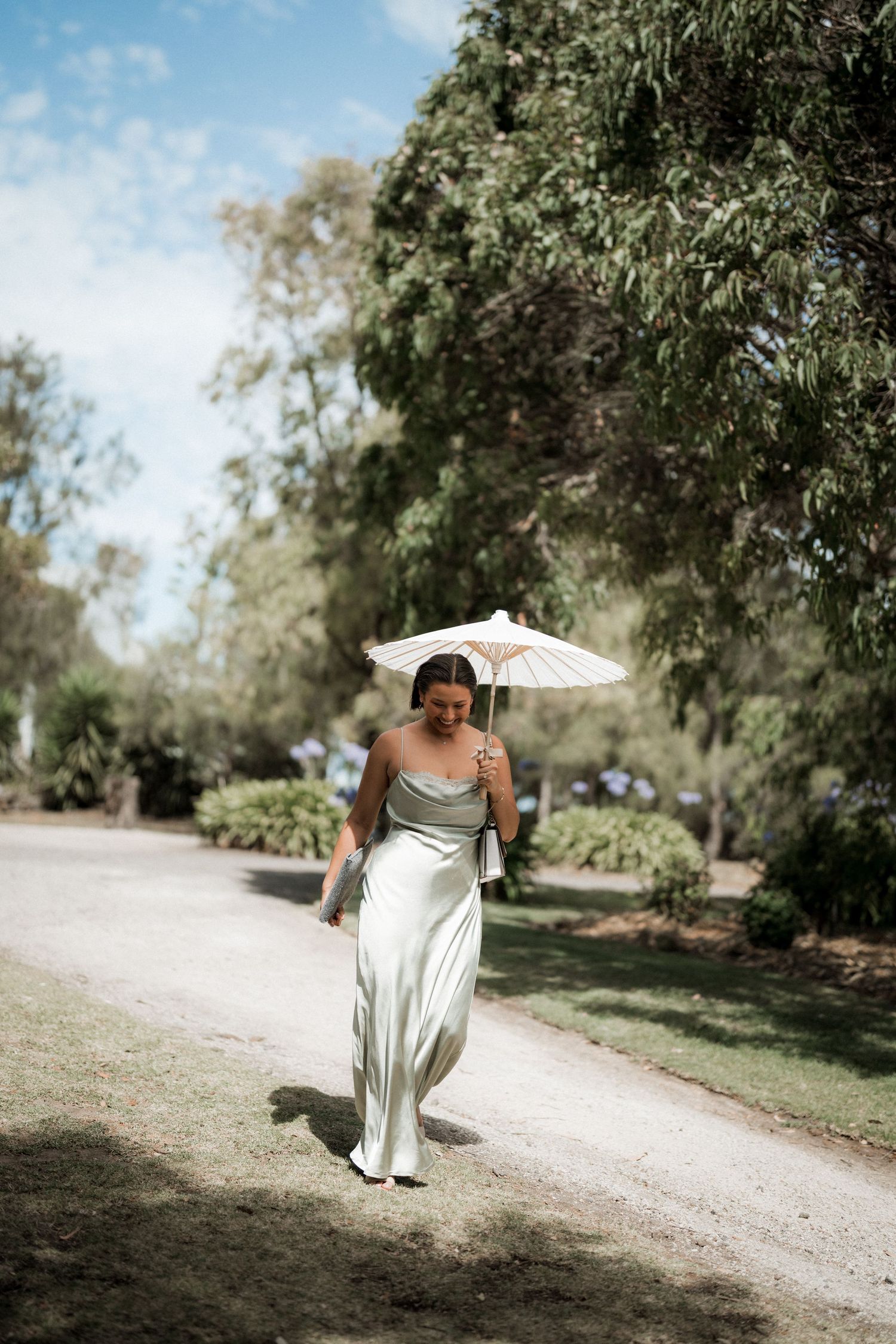 A white dress flowing in the breeze along a rustic dirt path surrounded by trees.