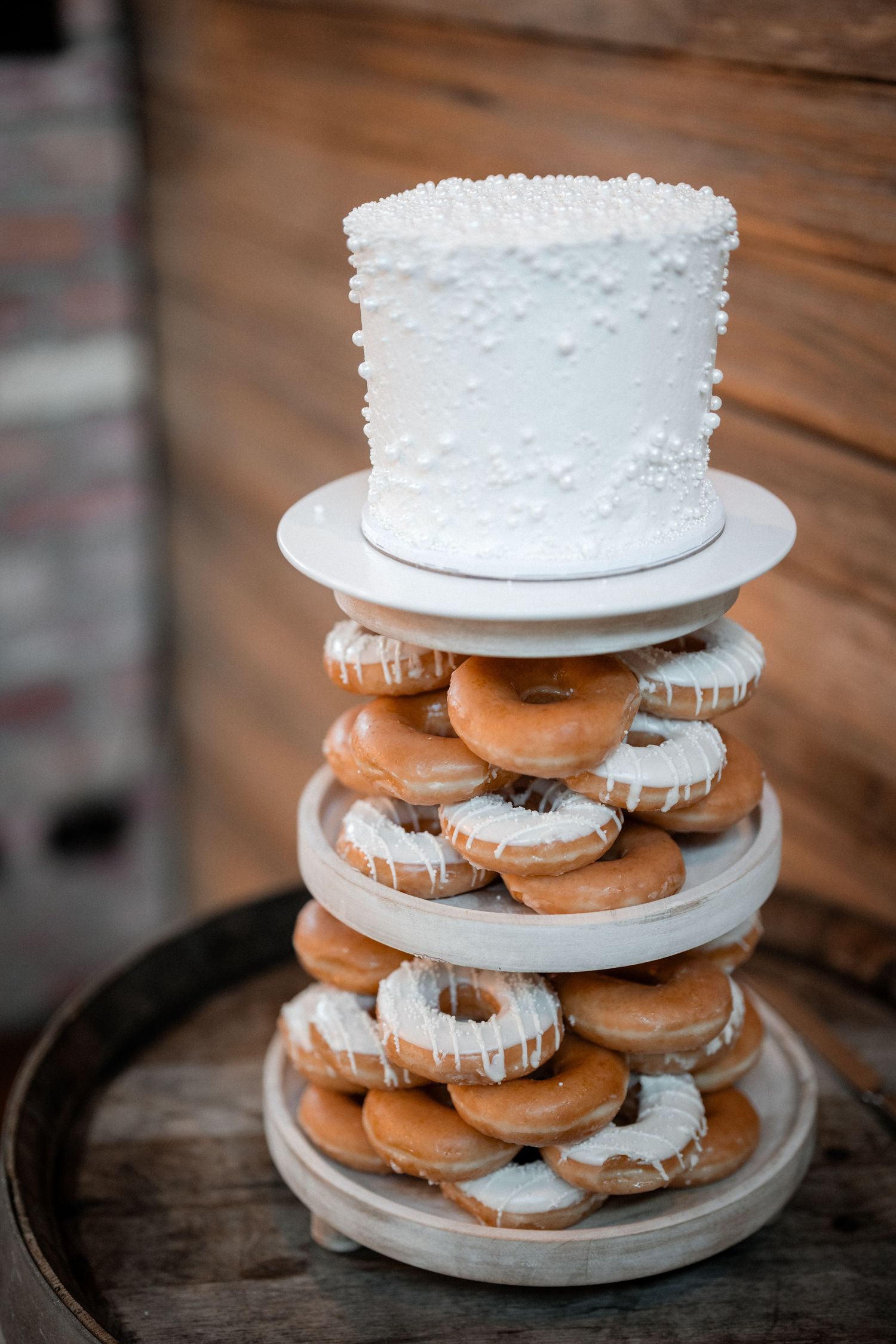 White wedding cake displayed atop tiered stand filled with decorated cookies and pastries.