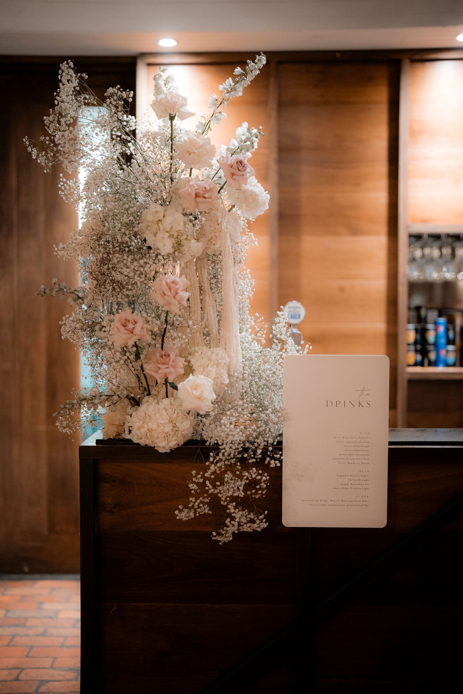 Elegant floral arrangement with white baby's breath and menu card displayed at wedding reception.