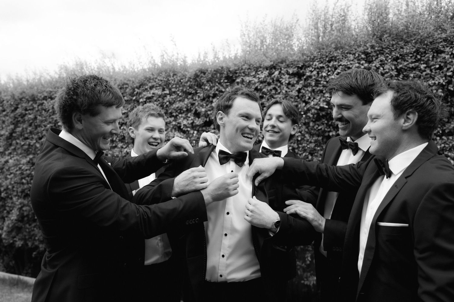 Wedding guests celebrate and dance together at a lively reception in black and white.