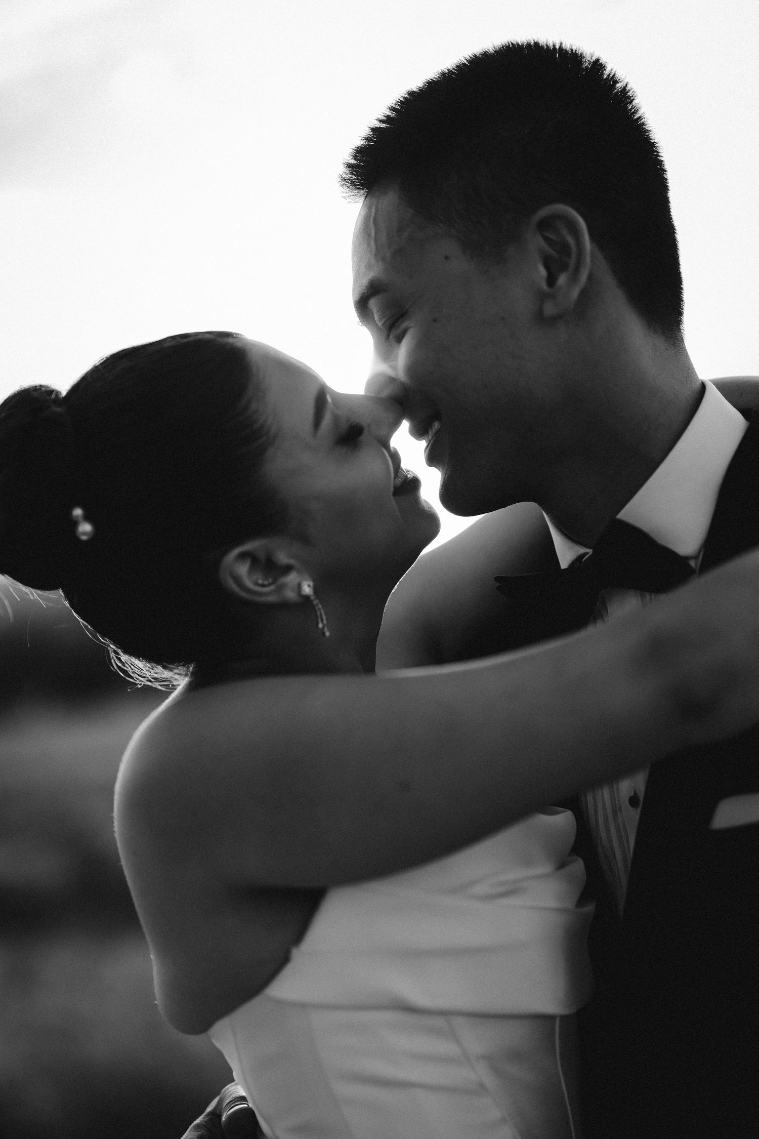 A romantic black and white portrait series captures an intimate moment between newlyweds at sunset.