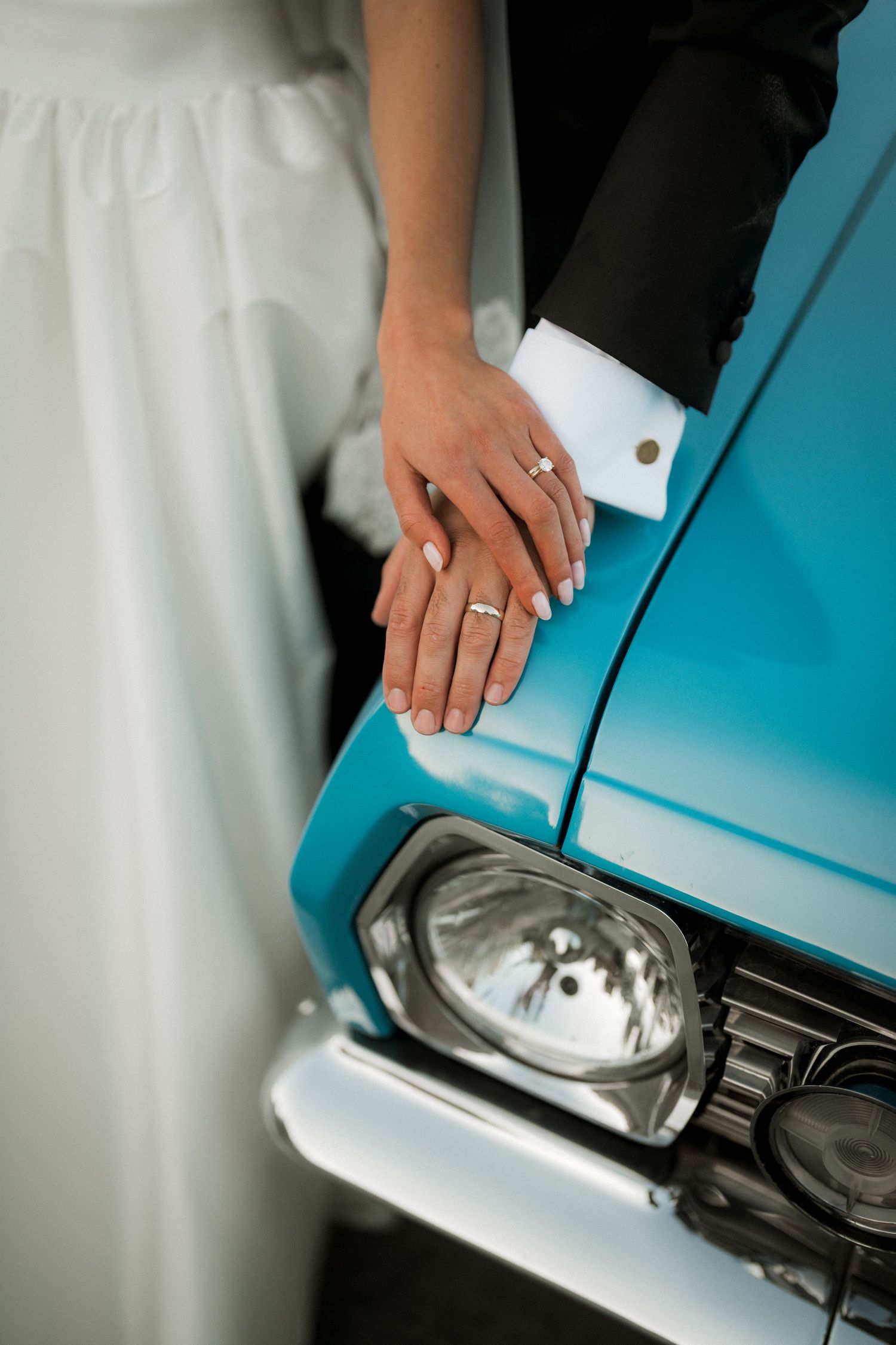Wedding ring detail shot against vintage turquoise car surface.