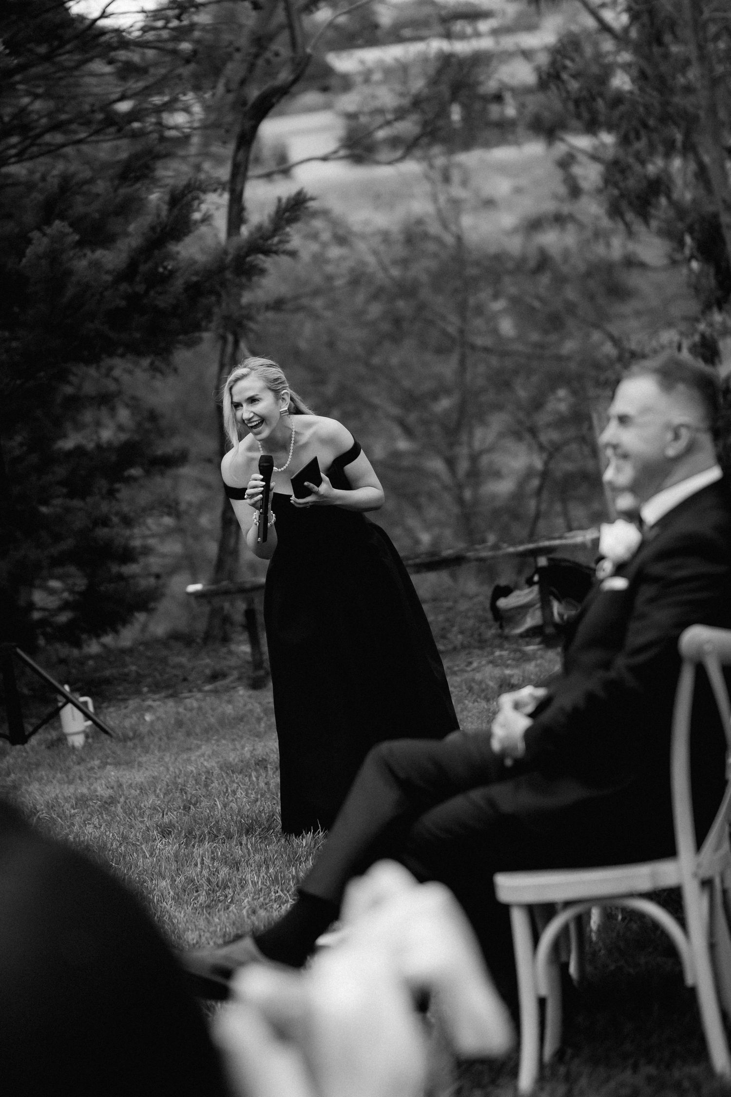 Wedding guests relaxing in chairs outdoors during black and white reception photography.