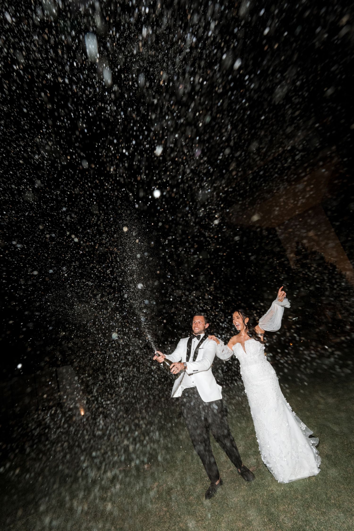 Night photography of wedding celebration with dramatic confetti shower effects.
