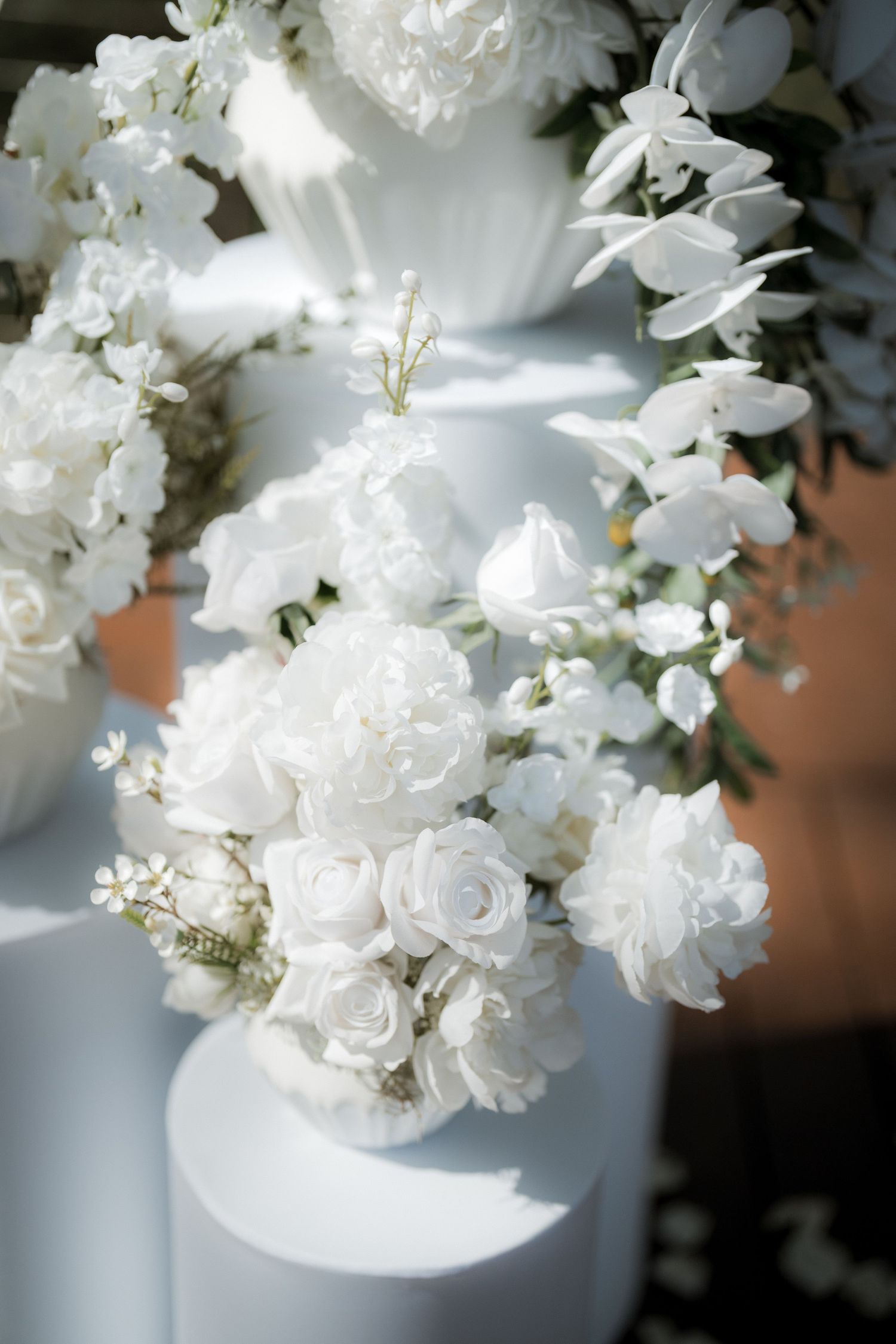 Elegant white floral arrangements with roses and delicate blooms in soft lighting.