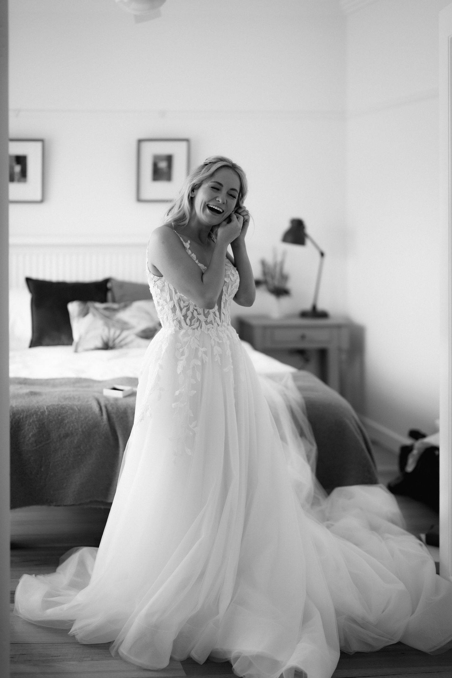 Joyful moment captured in black and white as bride laughs in flowing white wedding gown.