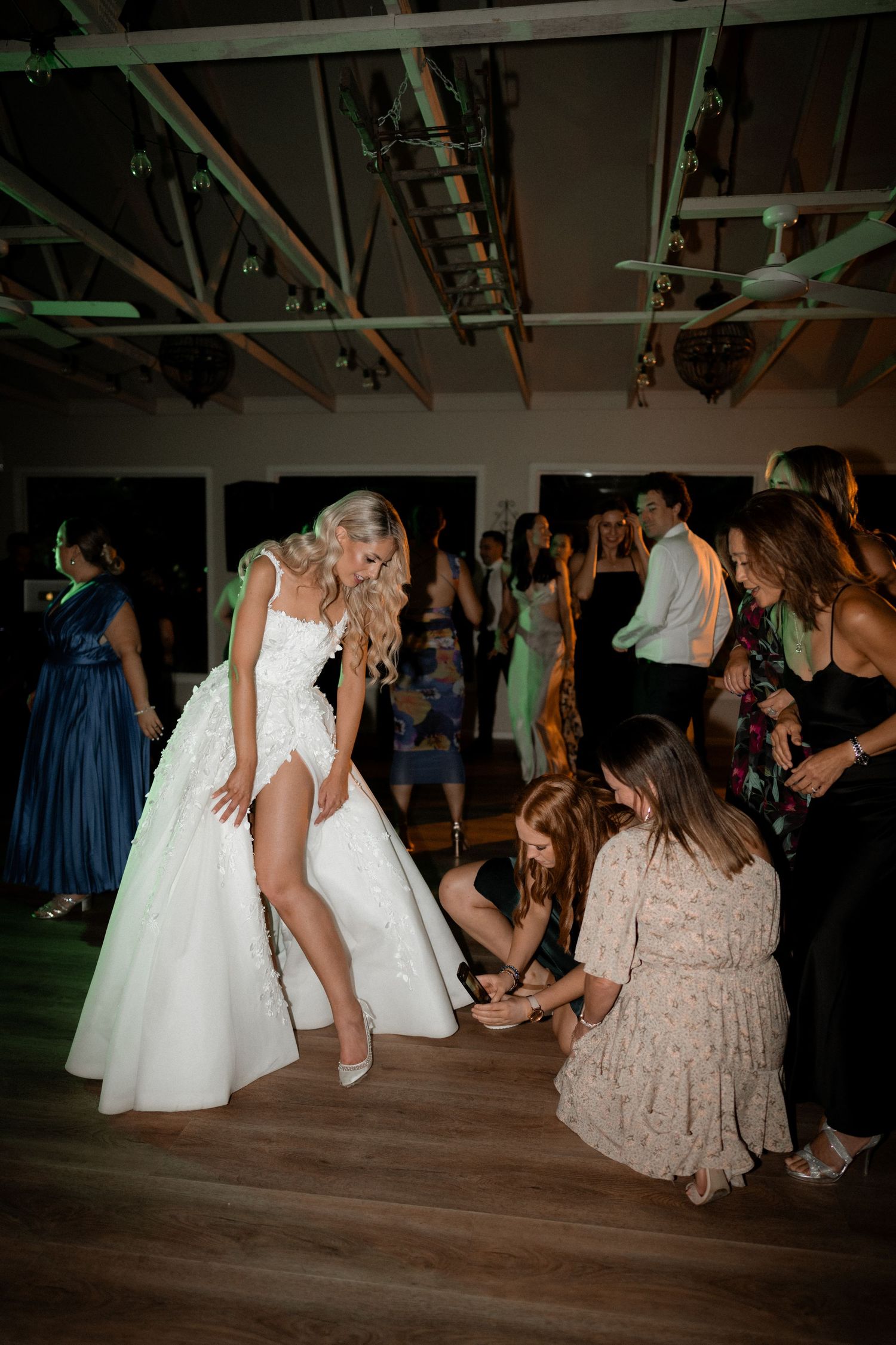 Lively dance floor moment during wedding reception with bride and guests.