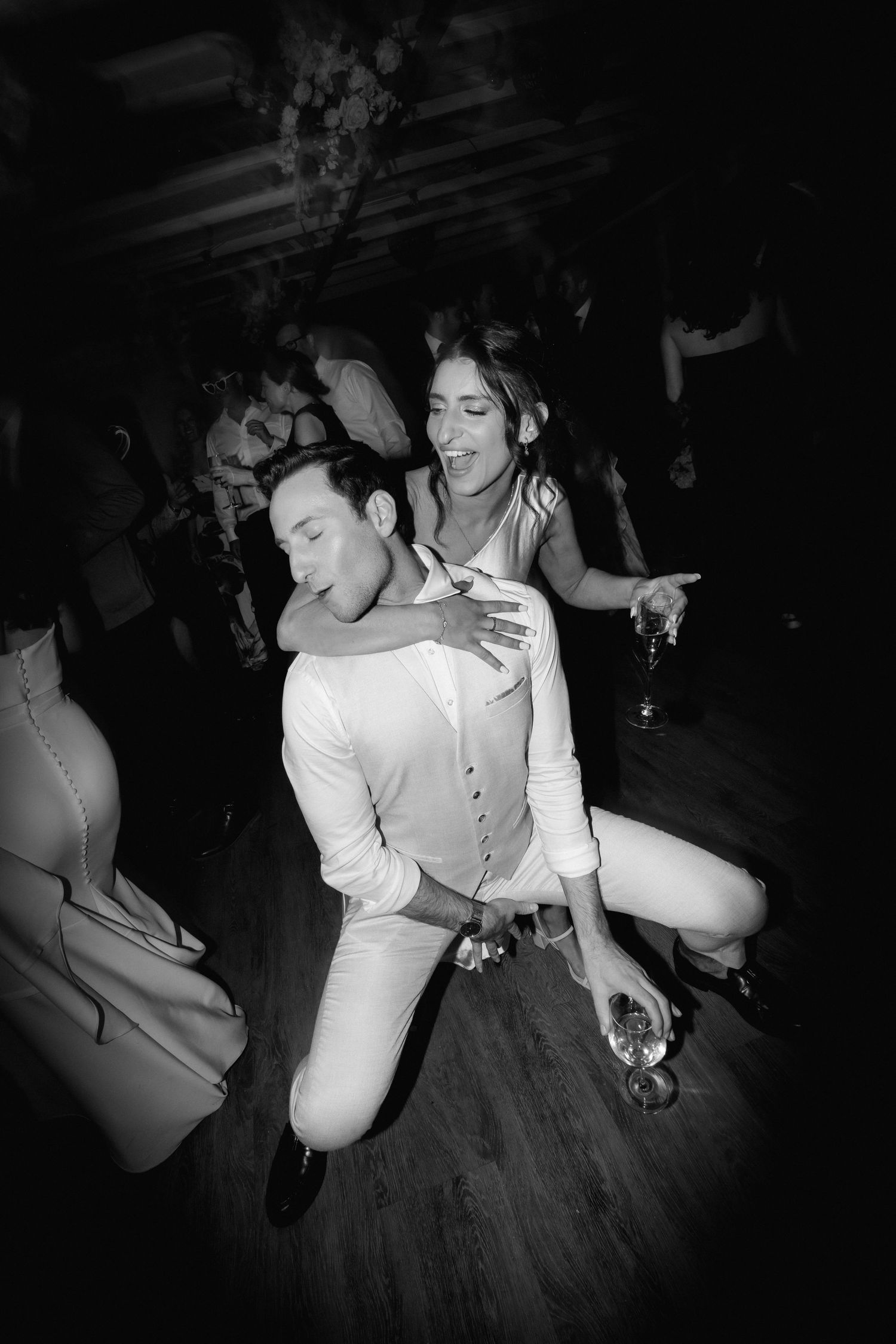 Black and white dance floor photos show wedding guests celebrating with energetic dance moves.