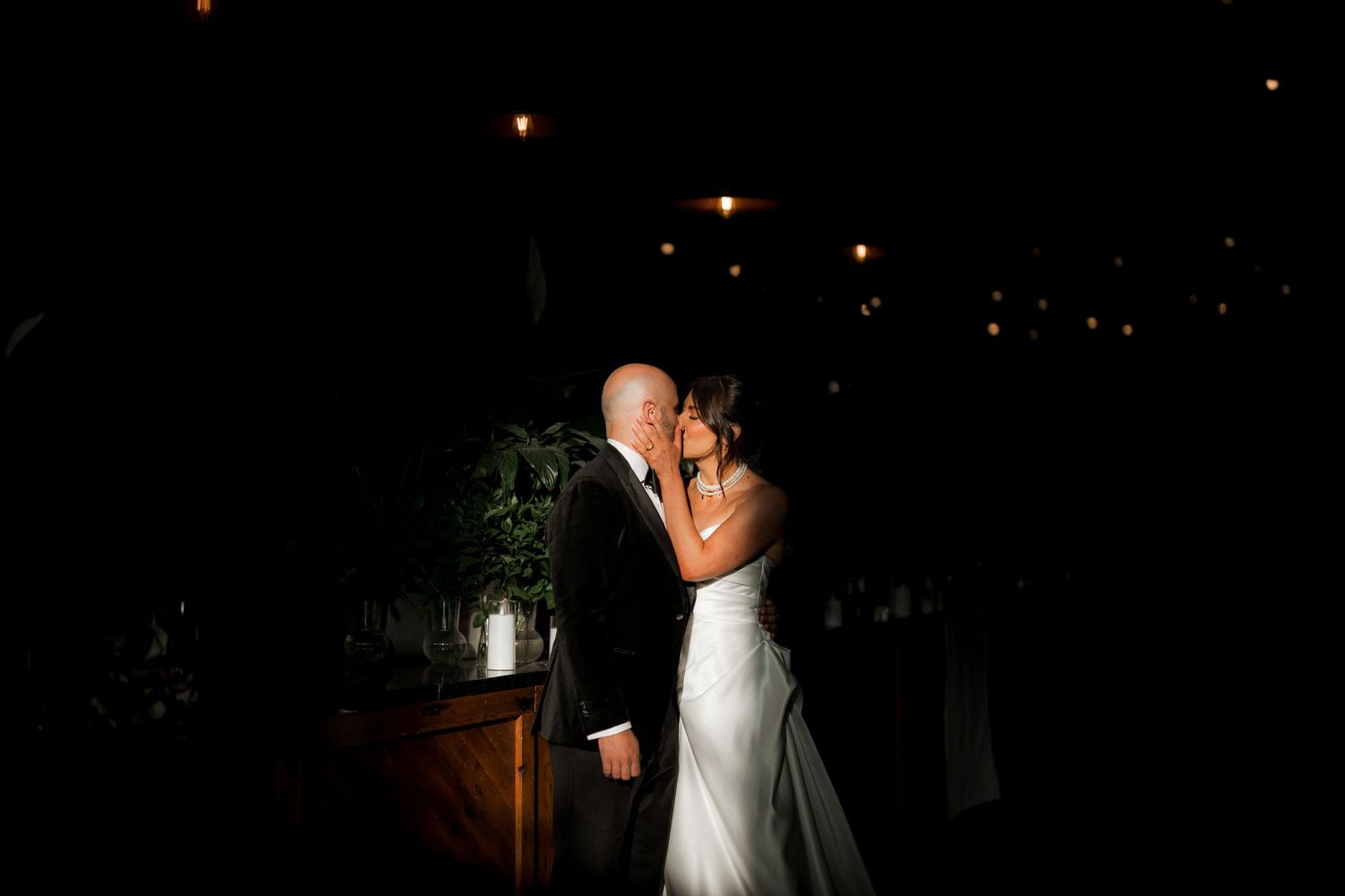 A romantic nighttime wedding photo with a couple embracing on a dimly lit outdoor patio.