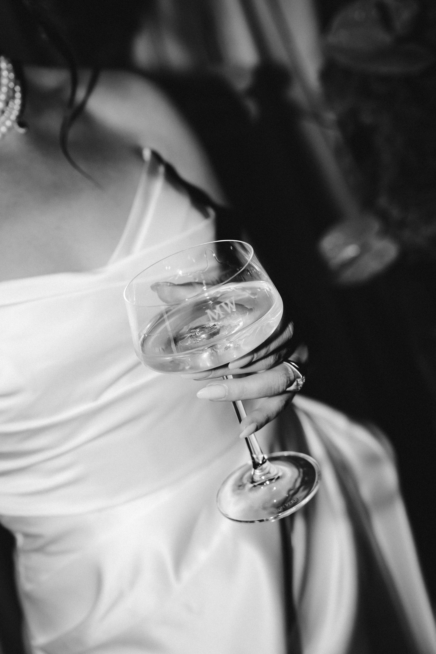 Close-up of champagne glasses being held against a white wedding dress.