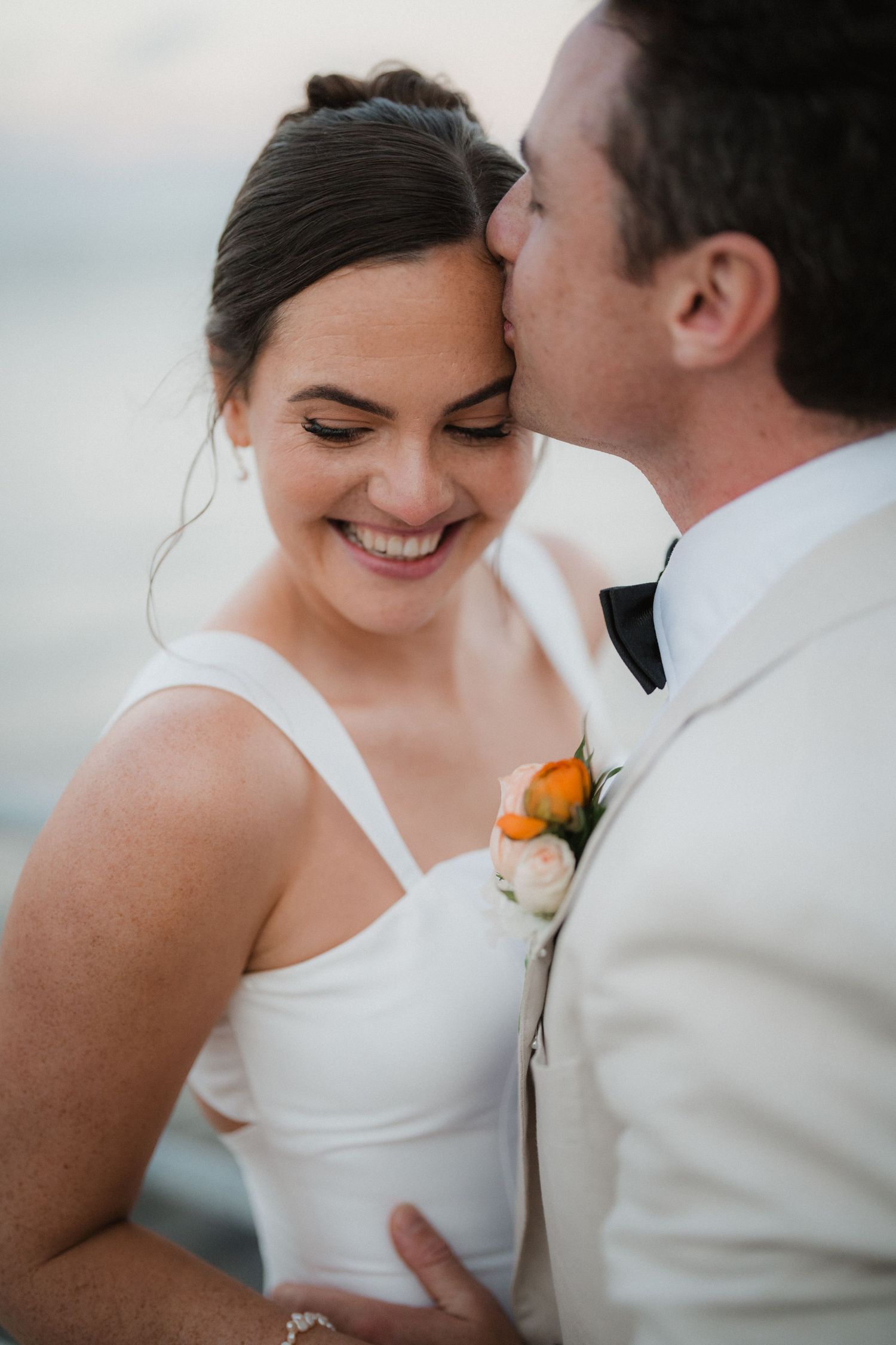 Romantic close-up of newlyweds sharing tender moment in soft lighting.
