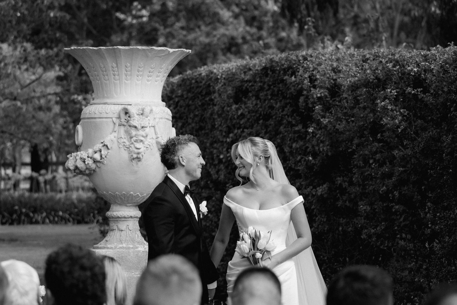 Black and white wedding photos displayed in a collage with romantic garden scenes and decorative urns.