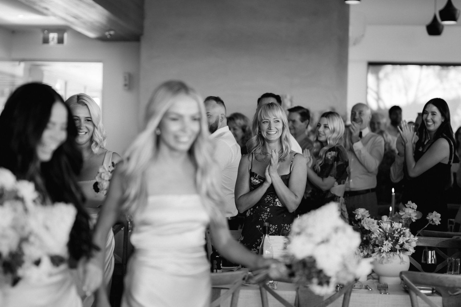 Black and white photo of wedding reception guests enjoying celebrations indoors.