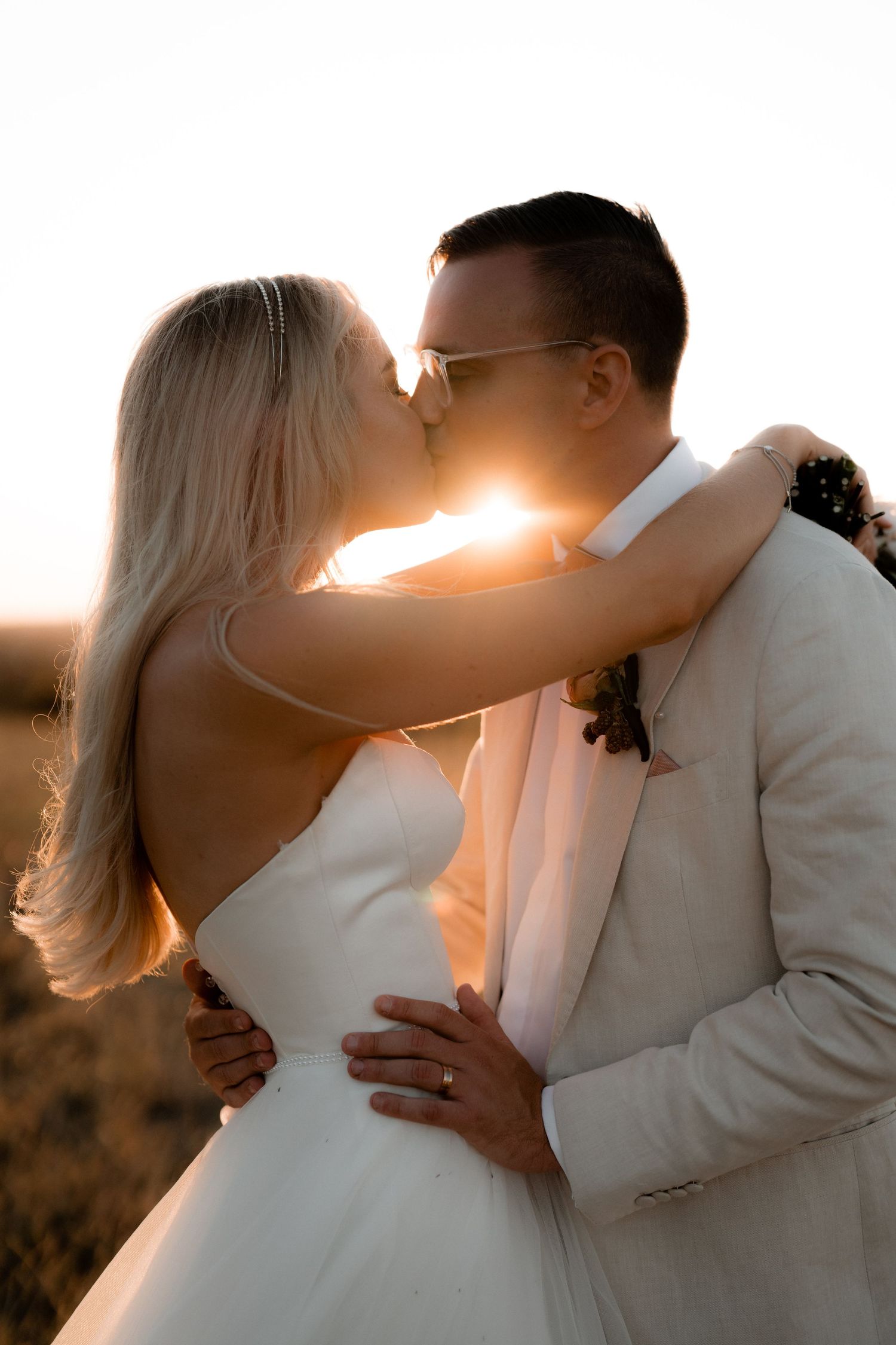 A romantic sunset silhouette of a couple in wedding attire.