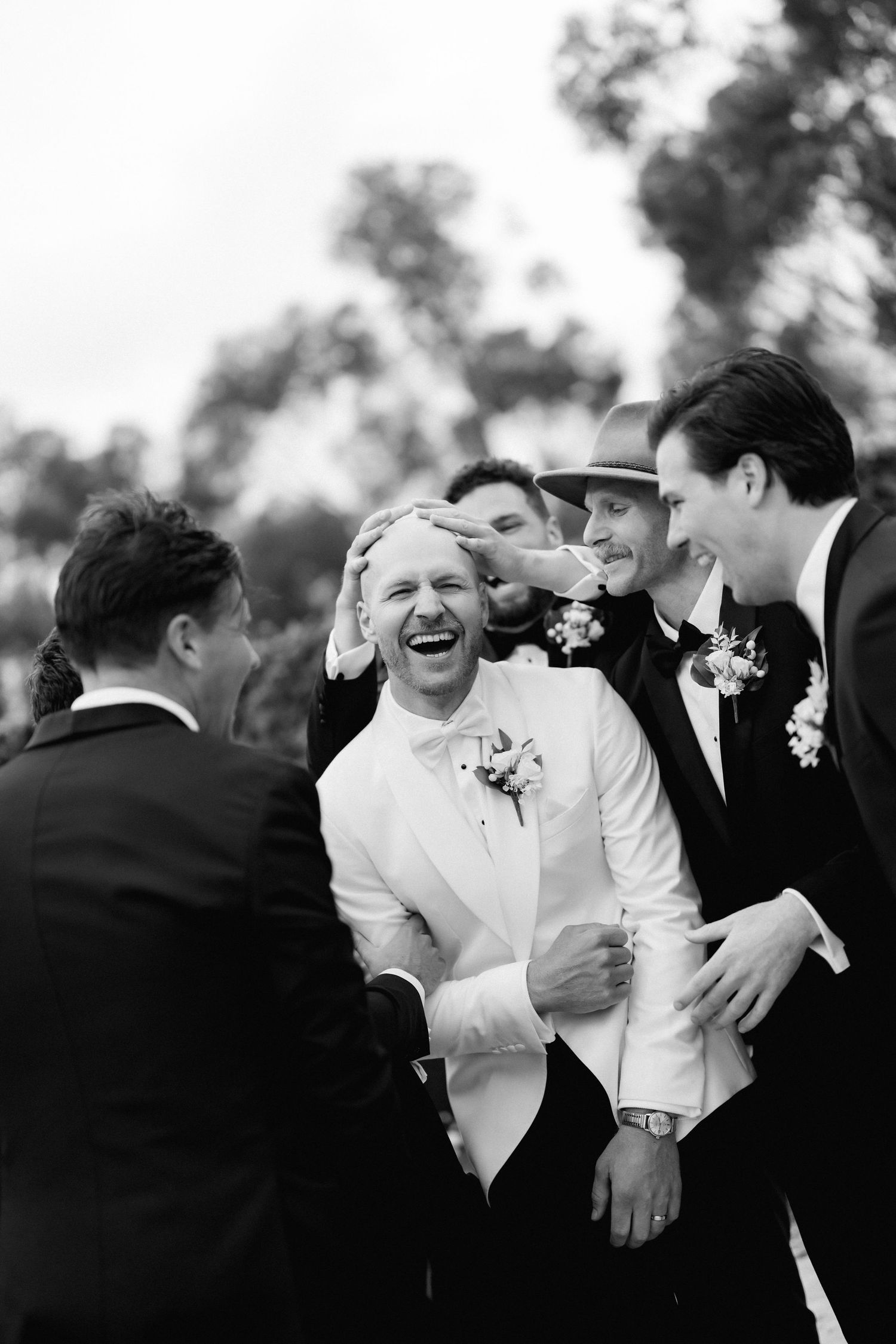 Candid black and white photo capturing joyful laughter during wedding celebration.