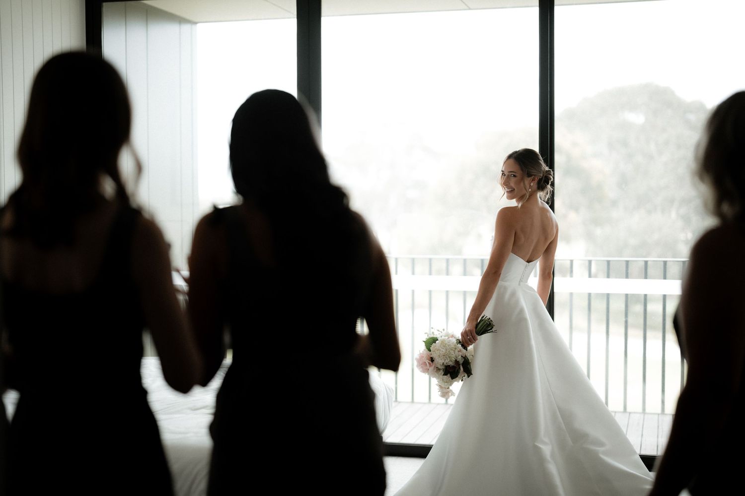 A wedding couple shares intimate moments by a balcony in dramatic black and white silhouettes.
