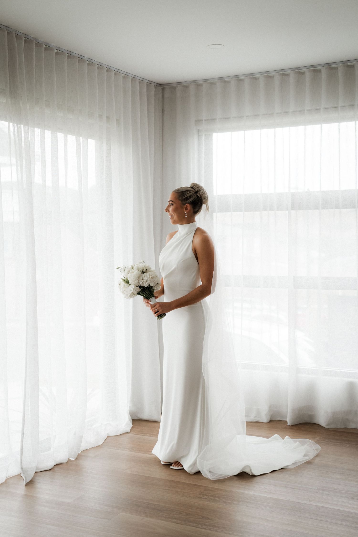 Elegant bridal portraits in a bright room with flowing white curtains and hardwood floors.
