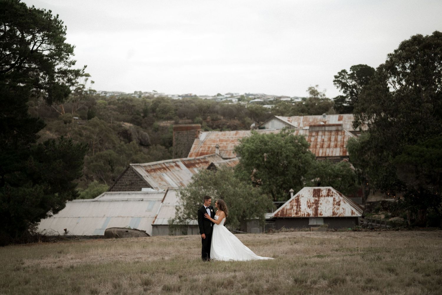 Panoramic view of a rustic wedding venue with buildings and trees in the distance.