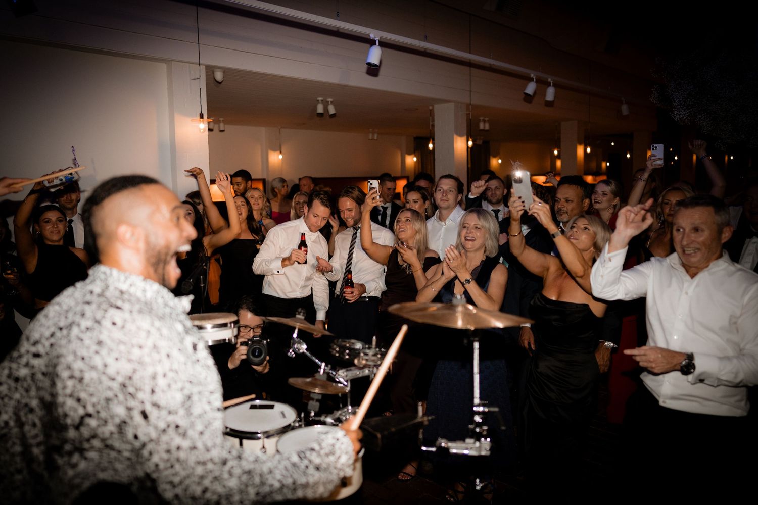 DJ performs for an energetic crowd of party guests dancing and celebrating at a nighttime event.