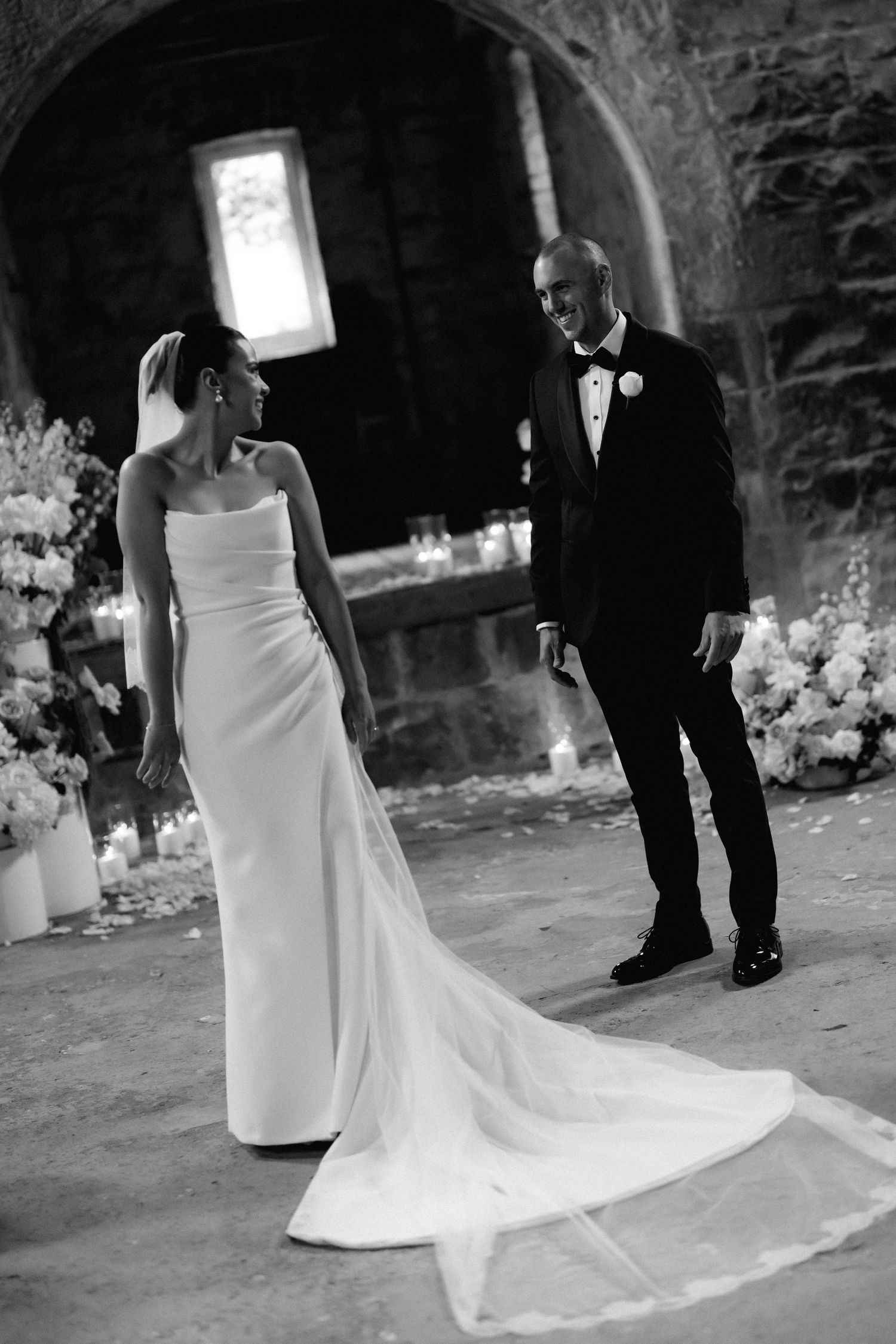 Black and white wedding photos showing elegant bride's dress train trailing on stone ground.