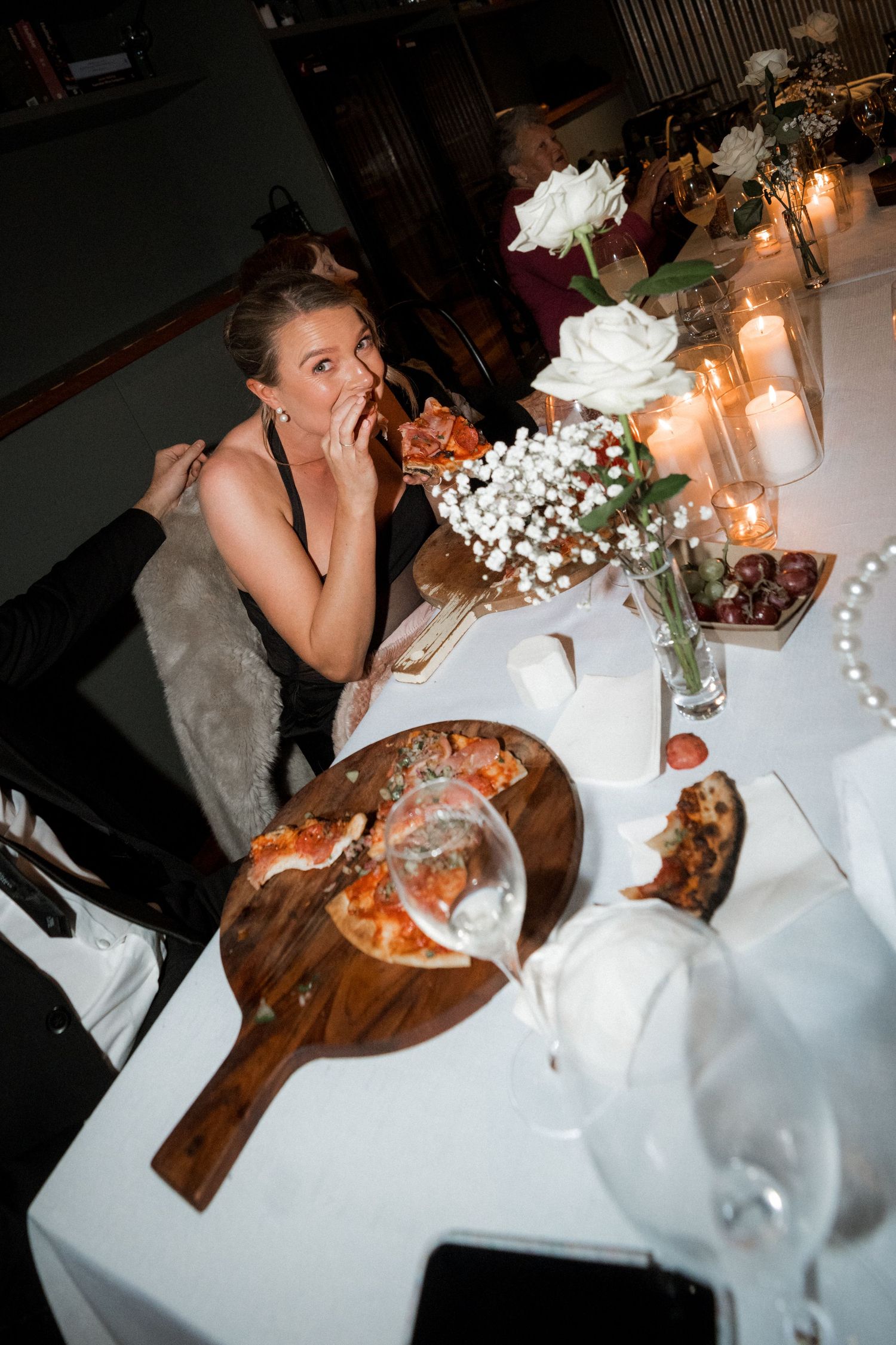 Candlelit wedding reception table with white linens and floral centerpieces as couple enjoys dinner.