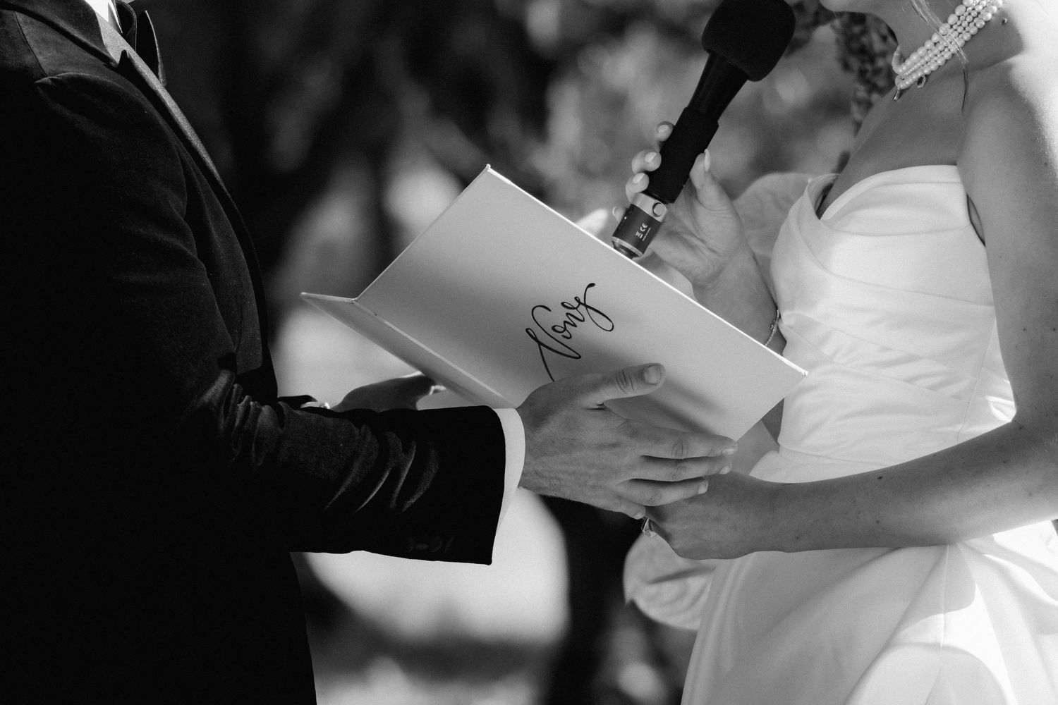 A couple in formal wedding attire exchanges rings during their marriage ceremony.