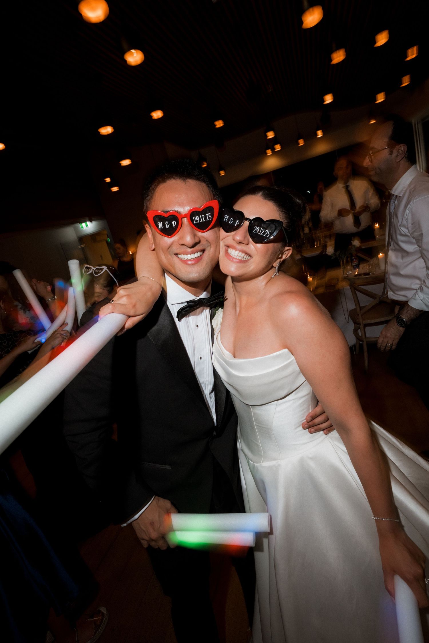 Newlyweds wearing fun sunglasses pose together on the dance floor at their wedding reception.
