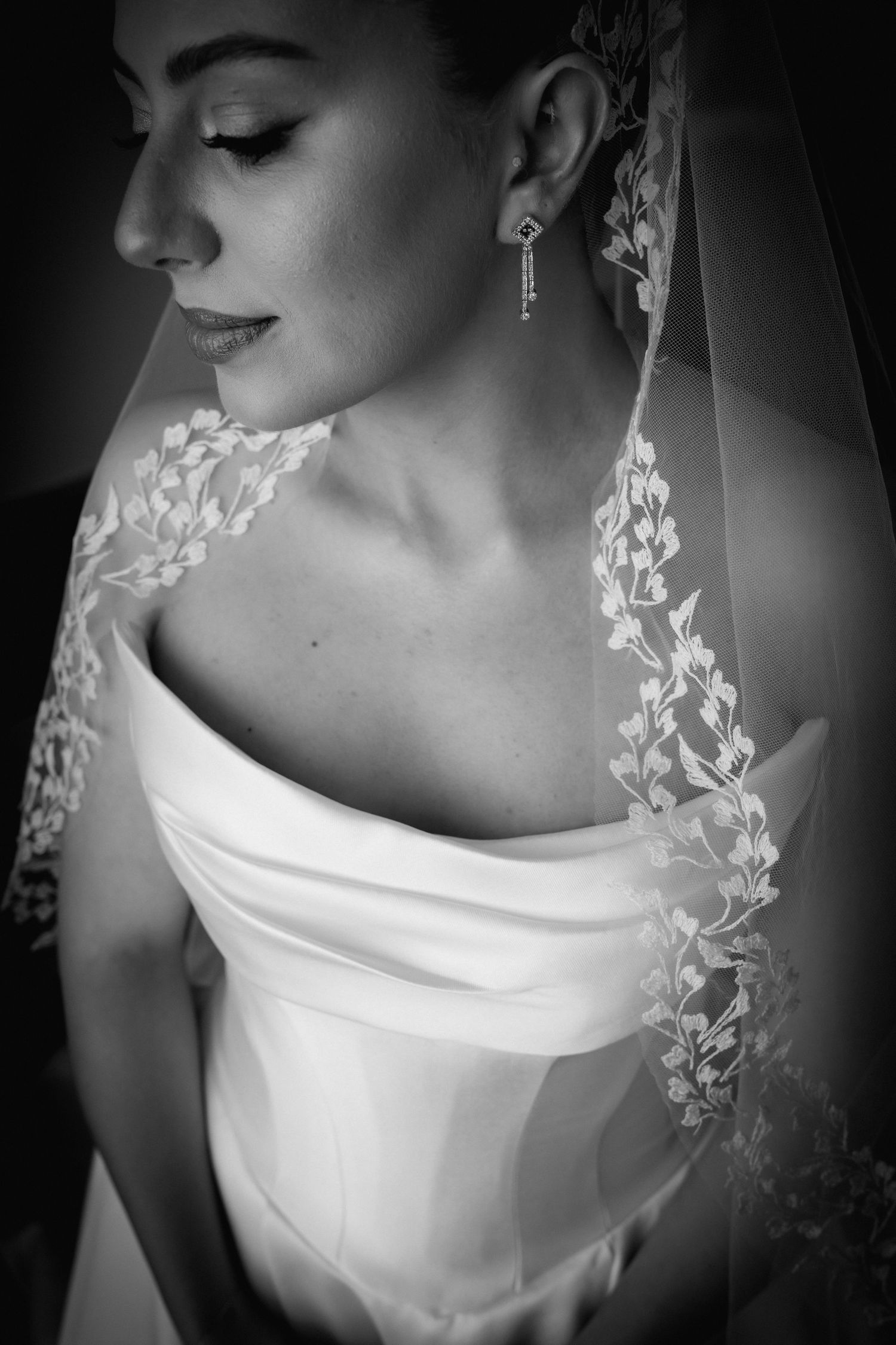 Artistic black and white bridal portrait showcasing lace veil details and off-shoulder gown.