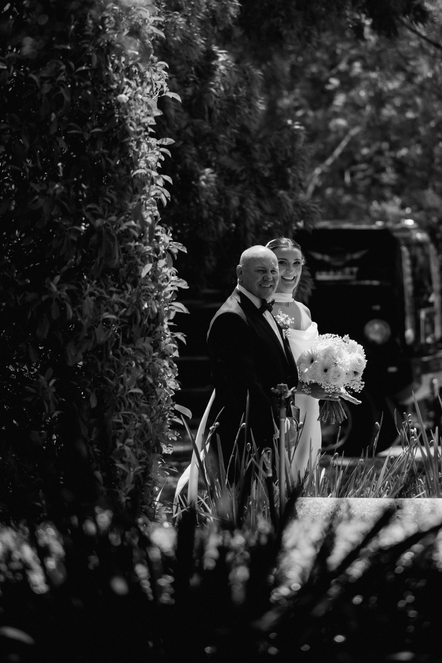 A black and white series of wedding photos showing a couple with a child in an outdoor garden setting.