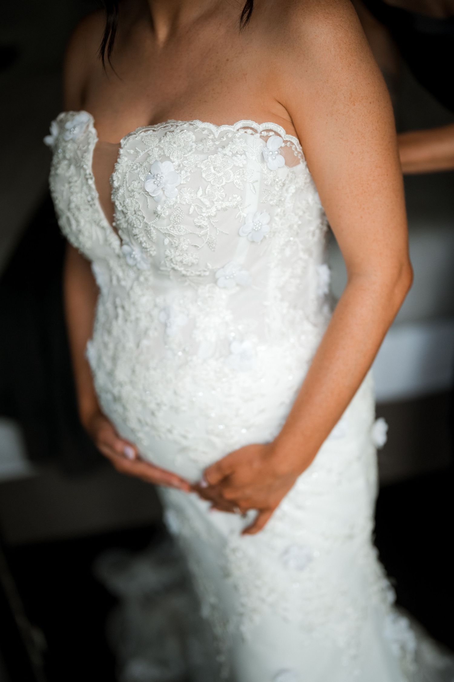 Close-up details of a white lace wedding dress with intricate embroidery patterns.