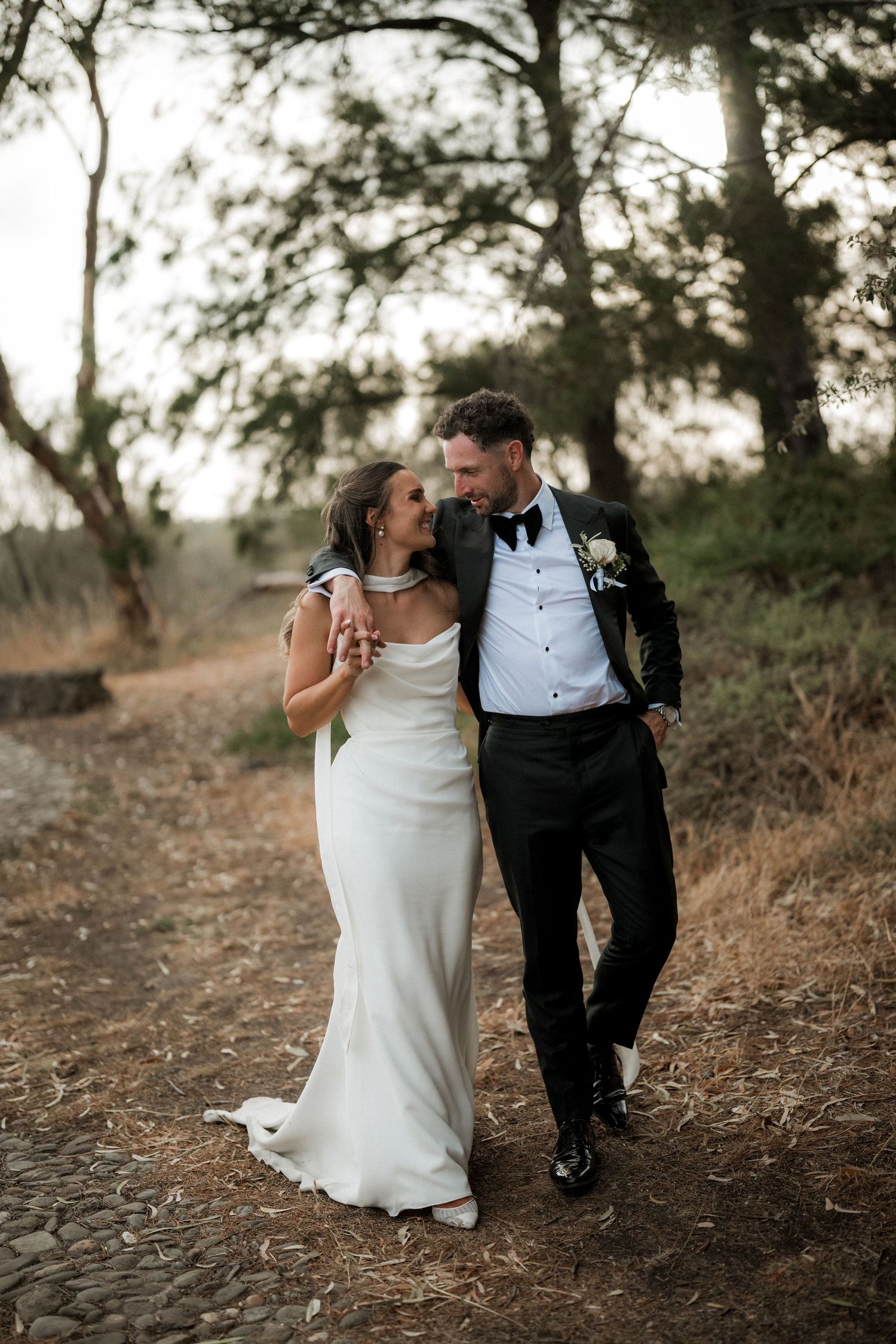 Newlywed couple shares intimate moments on a rustic path during their wedding photo session.