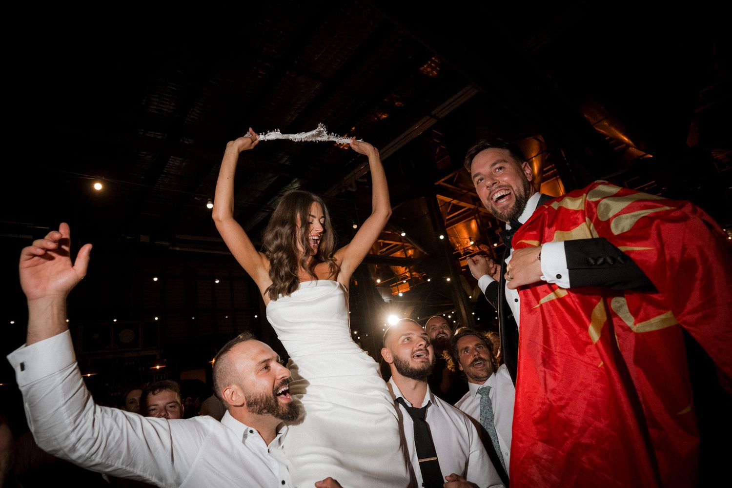 Wedding reception dance party with guests celebrating under dramatic lighting at night.