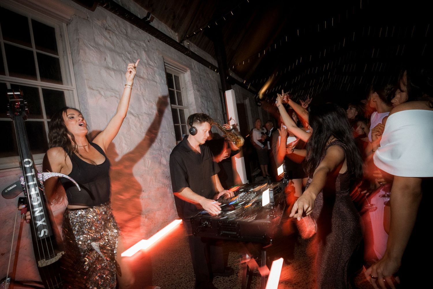 Energetic audience members dancing with hands in the air at a dimly lit music venue.